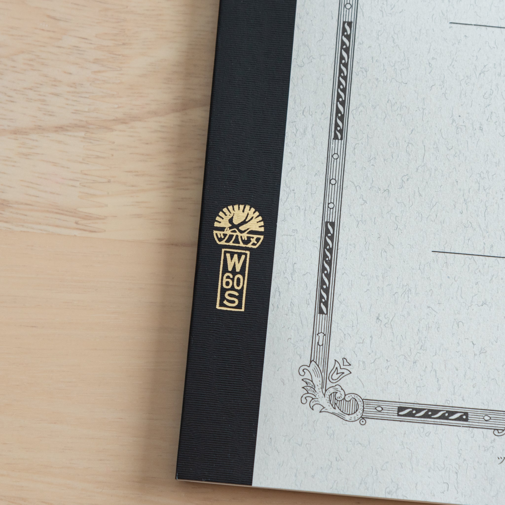 A close-up of the Tsubame Japanese notebook’s gold-stamped spine label, featuring the brand’s logo and model number, emphasizing fine Japanese stationery details.  