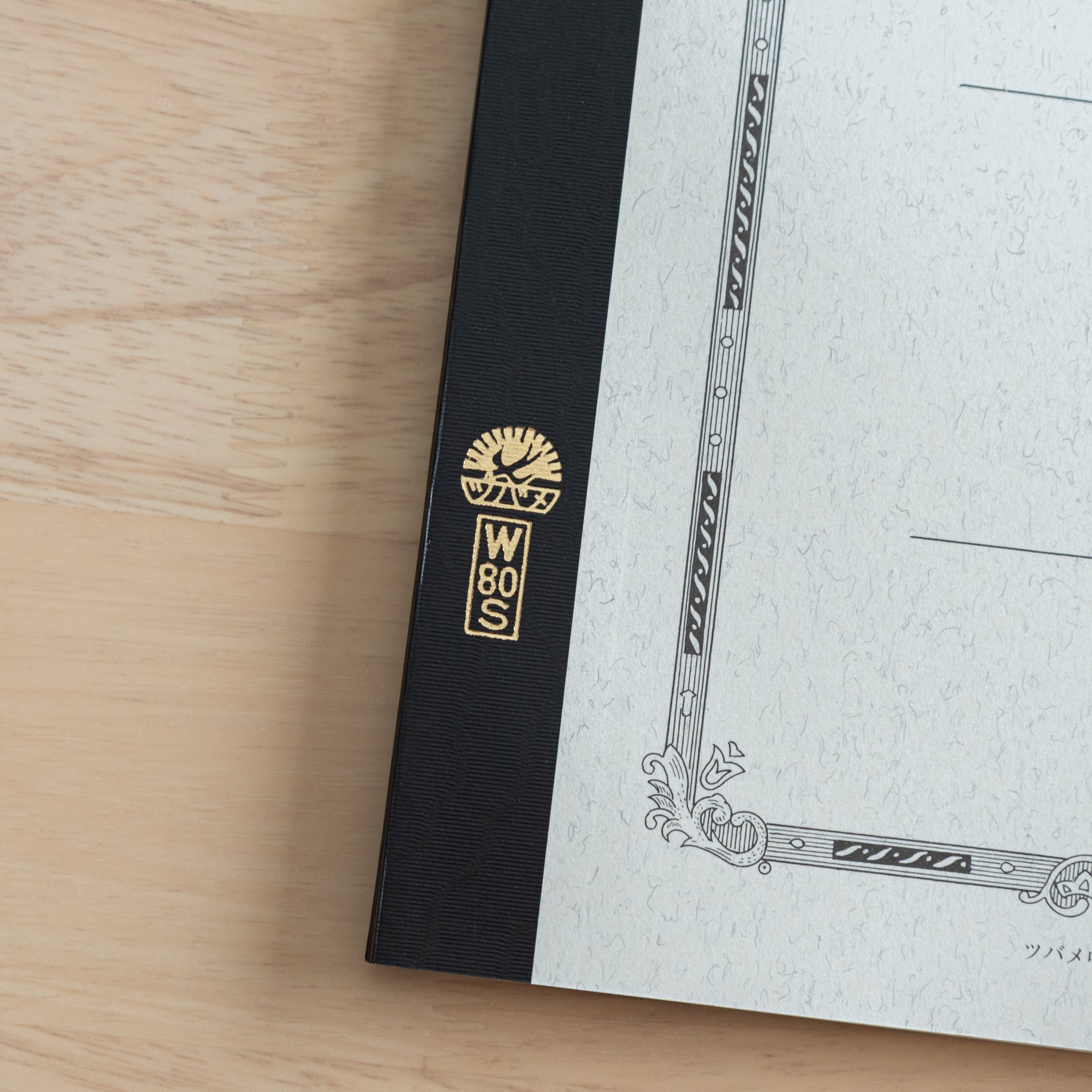 A close-up of the Tsubame Japanese notebook’s gold-stamped spine label, featuring the brand’s logo and model number, emphasizing fine Japanese stationery details.  