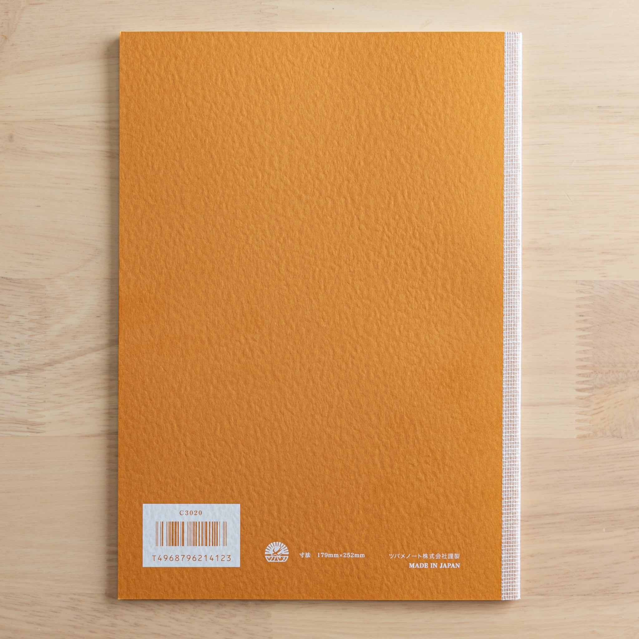 The back cover of a Tsubame Japanese notebook with an orange textured finish, barcode, and "Made in Japan" label. A classic piece of Japanese stationery.