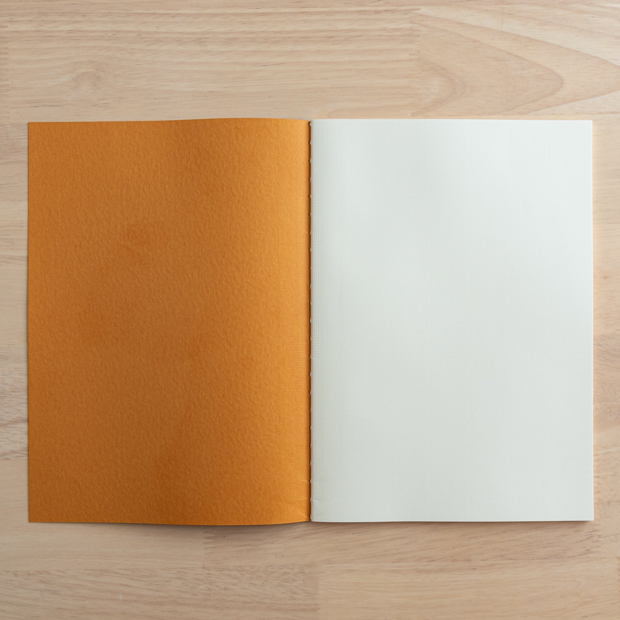 An open Tsubame Japanese notebook showing its orange cover and high-quality cream paper, known for smooth writing. A staple of Japanese stationery