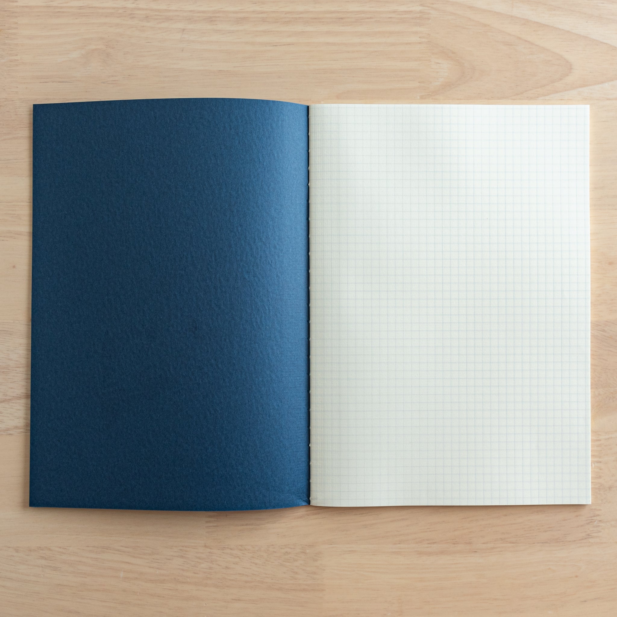 An open Tsubame Japanese notebook showing its navy blue cover and cream-colored grid paper, perfect for precise writing. A hallmark of Japanese stationery.  