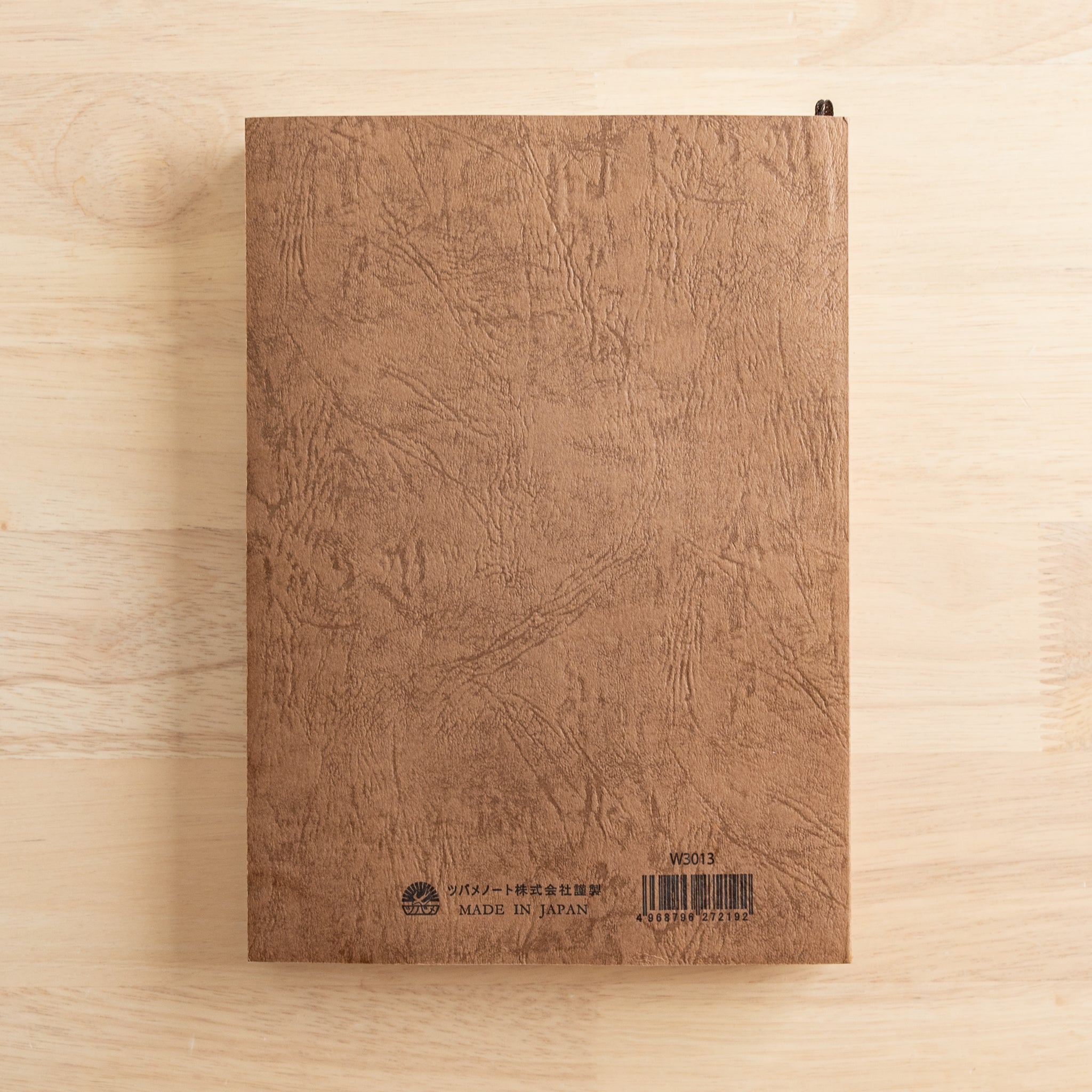 The back cover of a Japanese notebook with a textured brown design, featuring a barcode, brand logo, and "Made in Japan" text, showcasing fine Japanese stationery.  