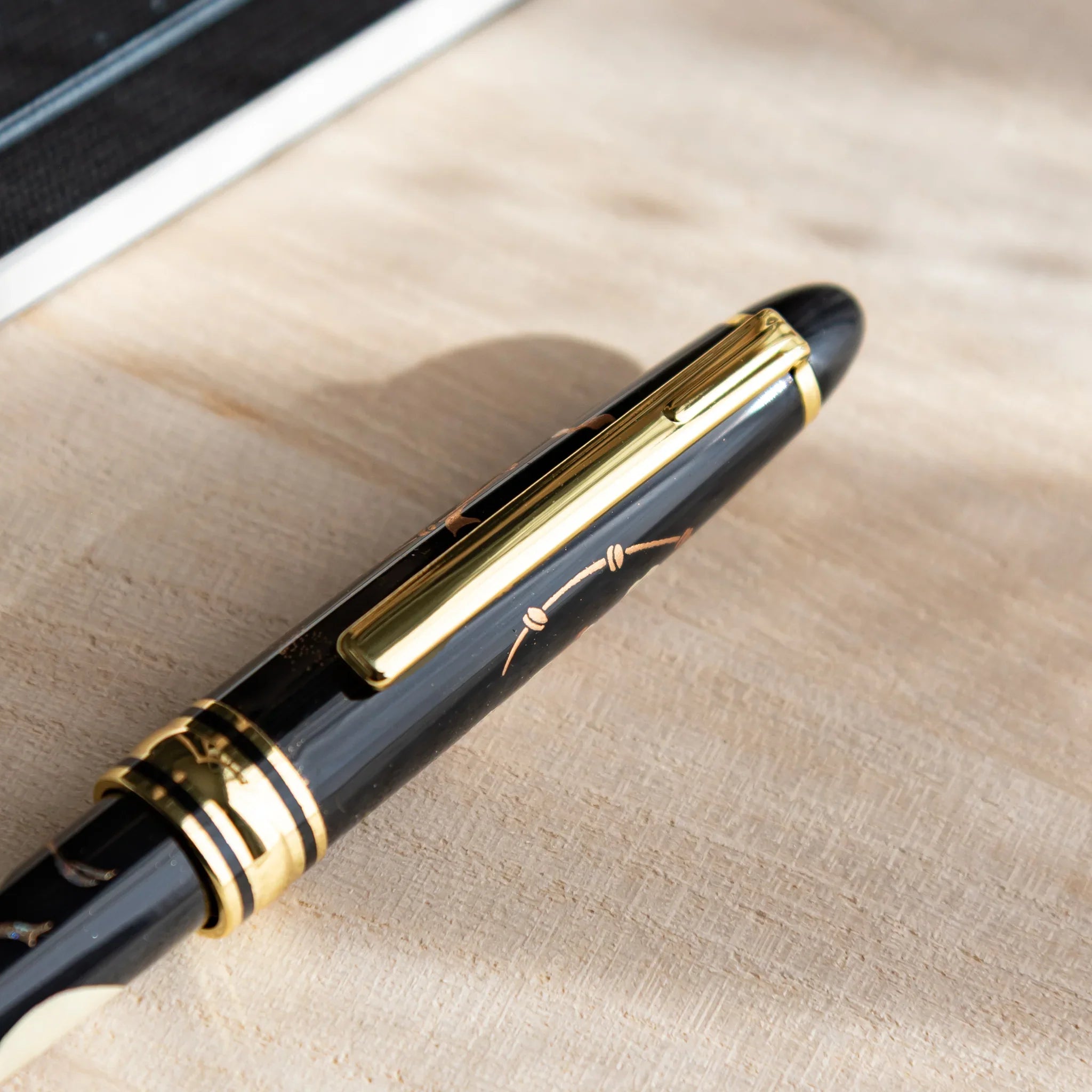 Close-up of Japanese Ballpoint Pen cap with gold clip resting on the desk.