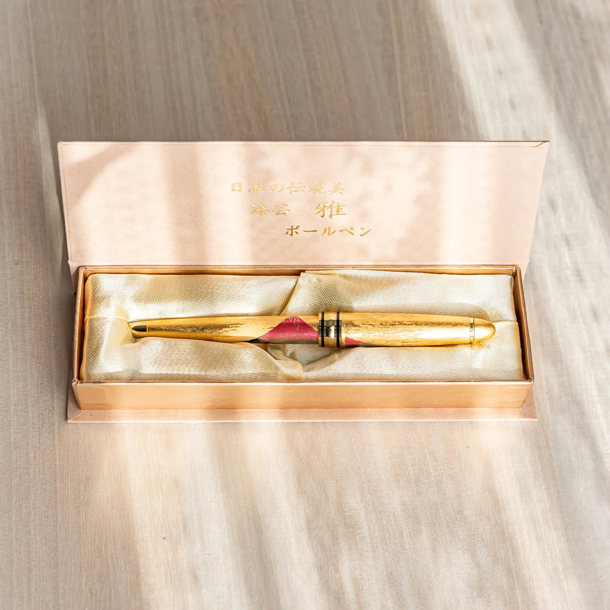Gold Leaf Mt. Fuji Japanese Ballpoint Pen in a satin-lined gold gift box, featuring red Fuji artwork and a shimmering gold body.