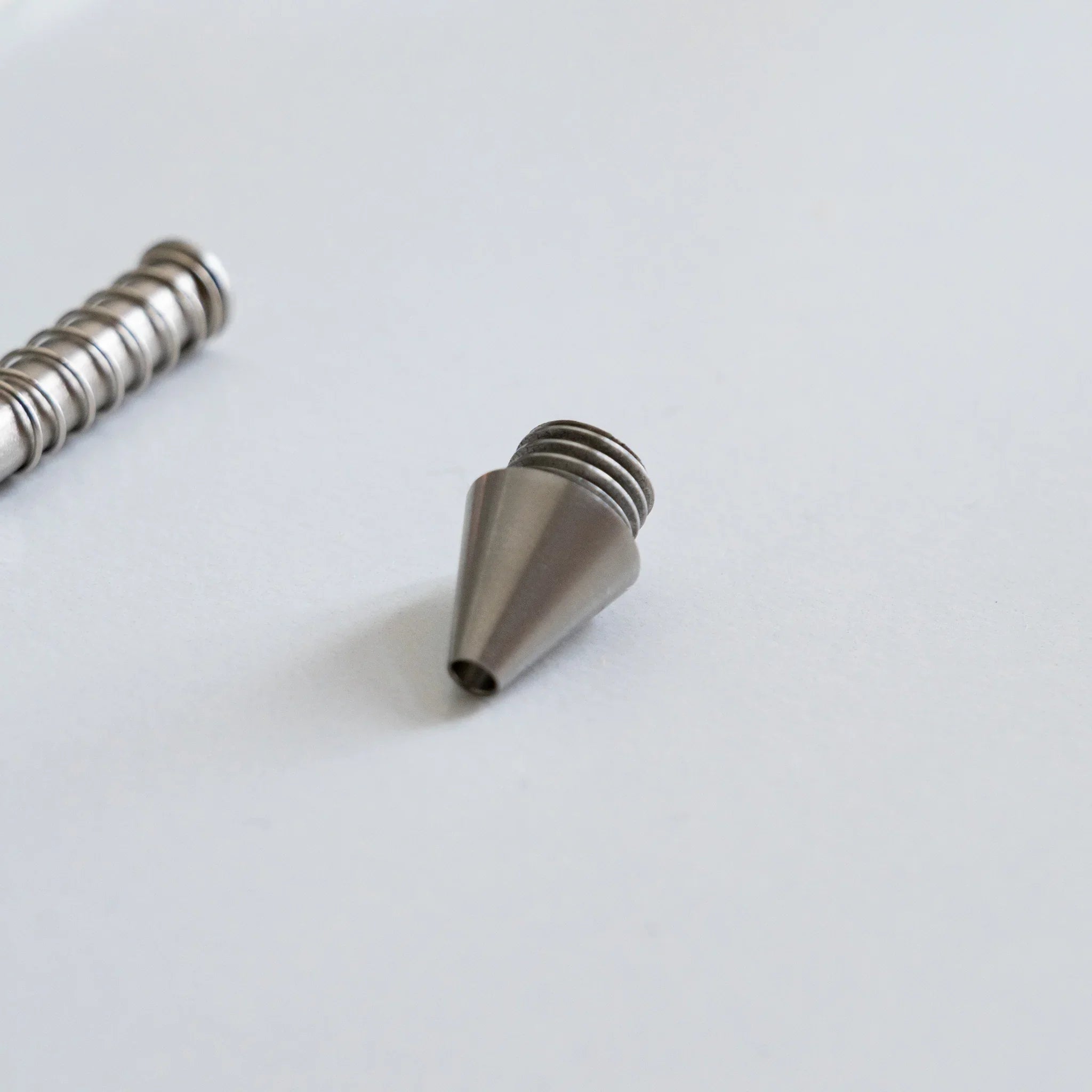 Overhead flat lay view of assembled spring coil mechanism and polished metal ballpoint nib pieces grouped