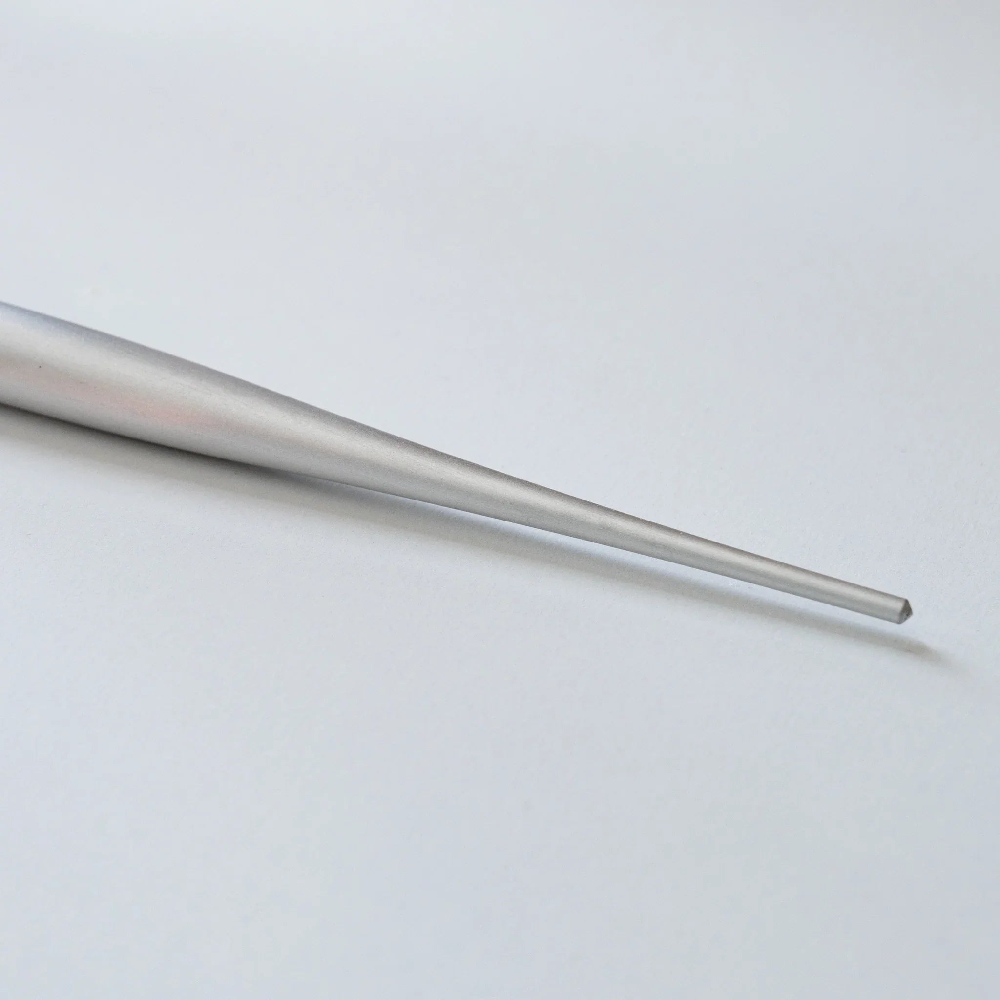 Side profile view of aerospace-grade duralumin ballpoint pen resting horizontally on white paper background