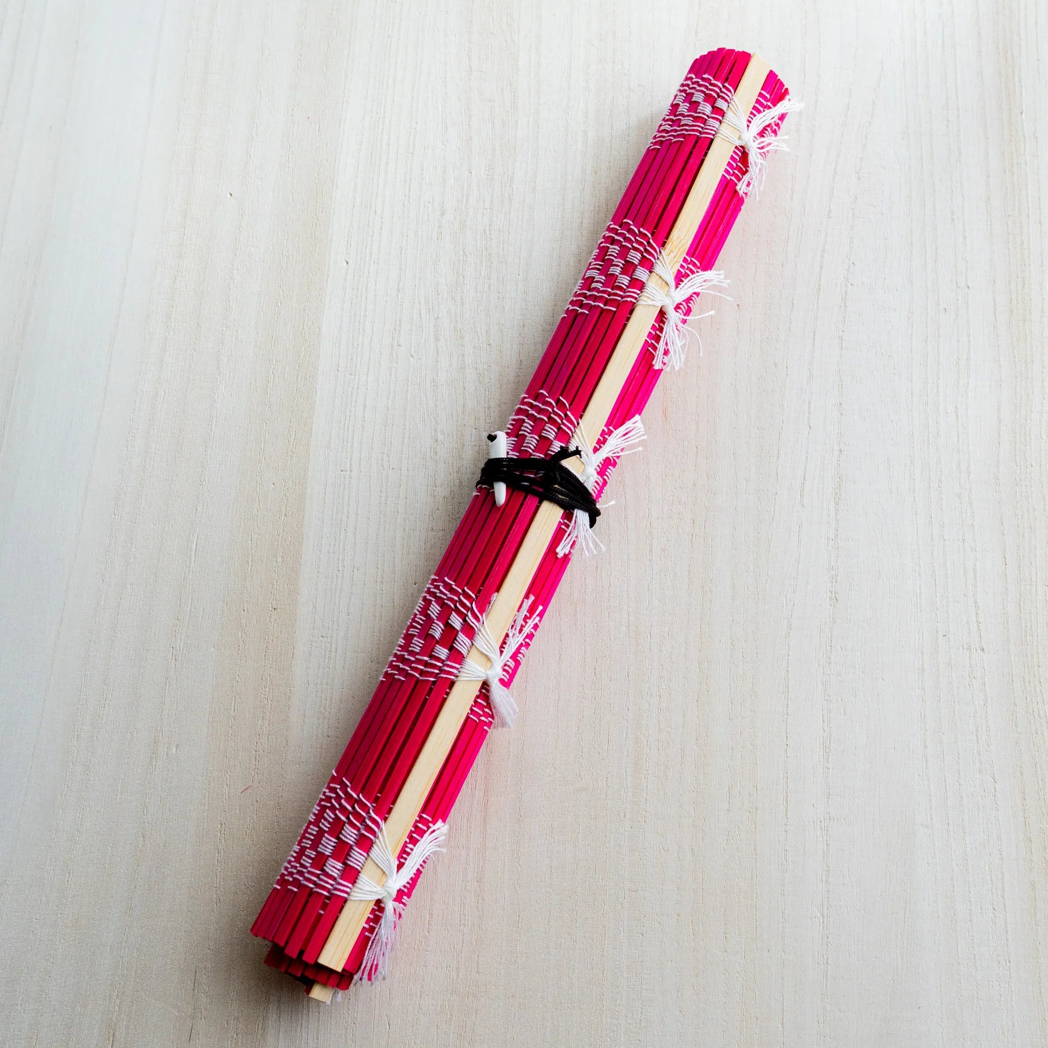 Akashiya bamboo brush holder roll, red, angled view on a light wood background