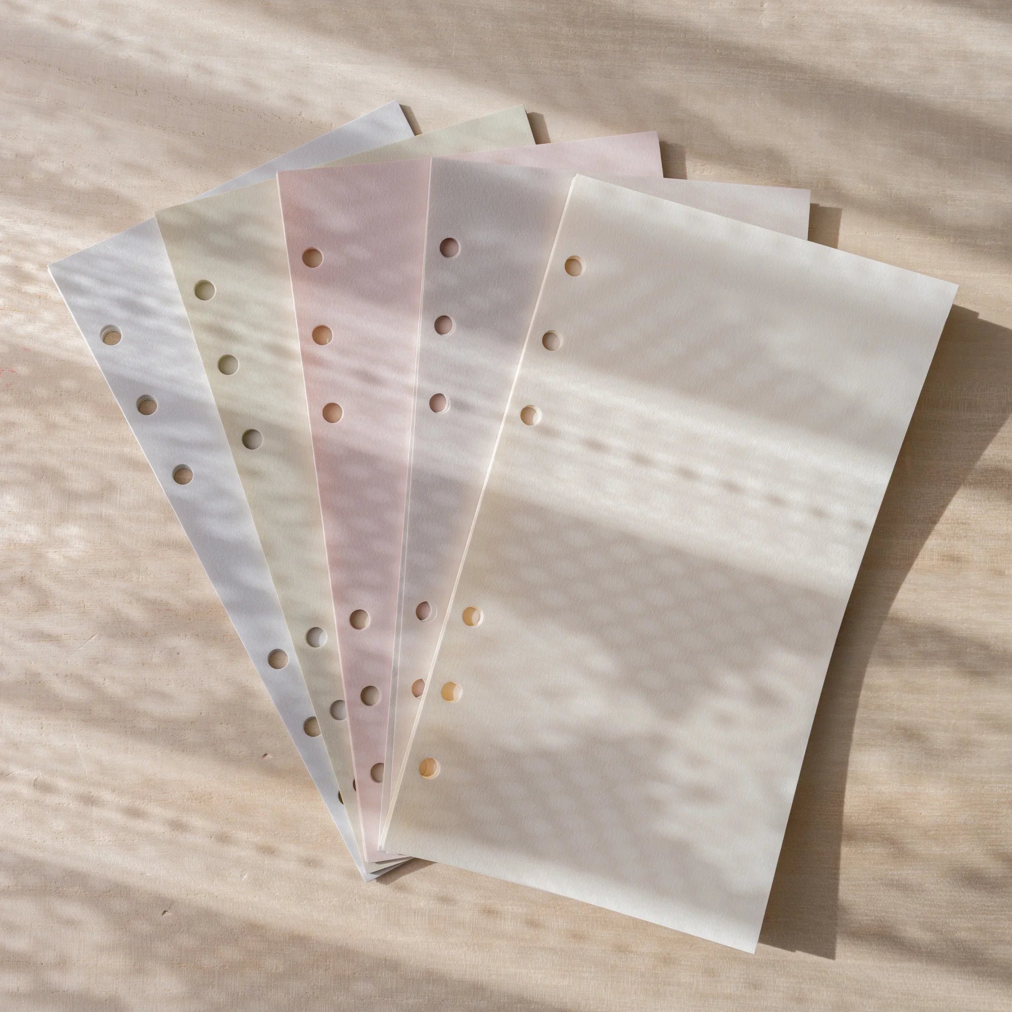 Five Araveal planner refill paper colors fanned out: natural, ash gray, primrose, sage green, and slate blue.