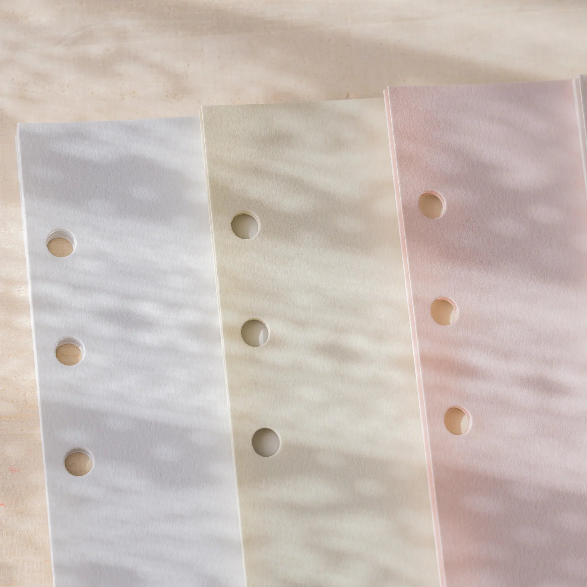 Three Araveal planner refill colors close-up: slate blue, primrose, and sage green showing 6-hole binder punch.