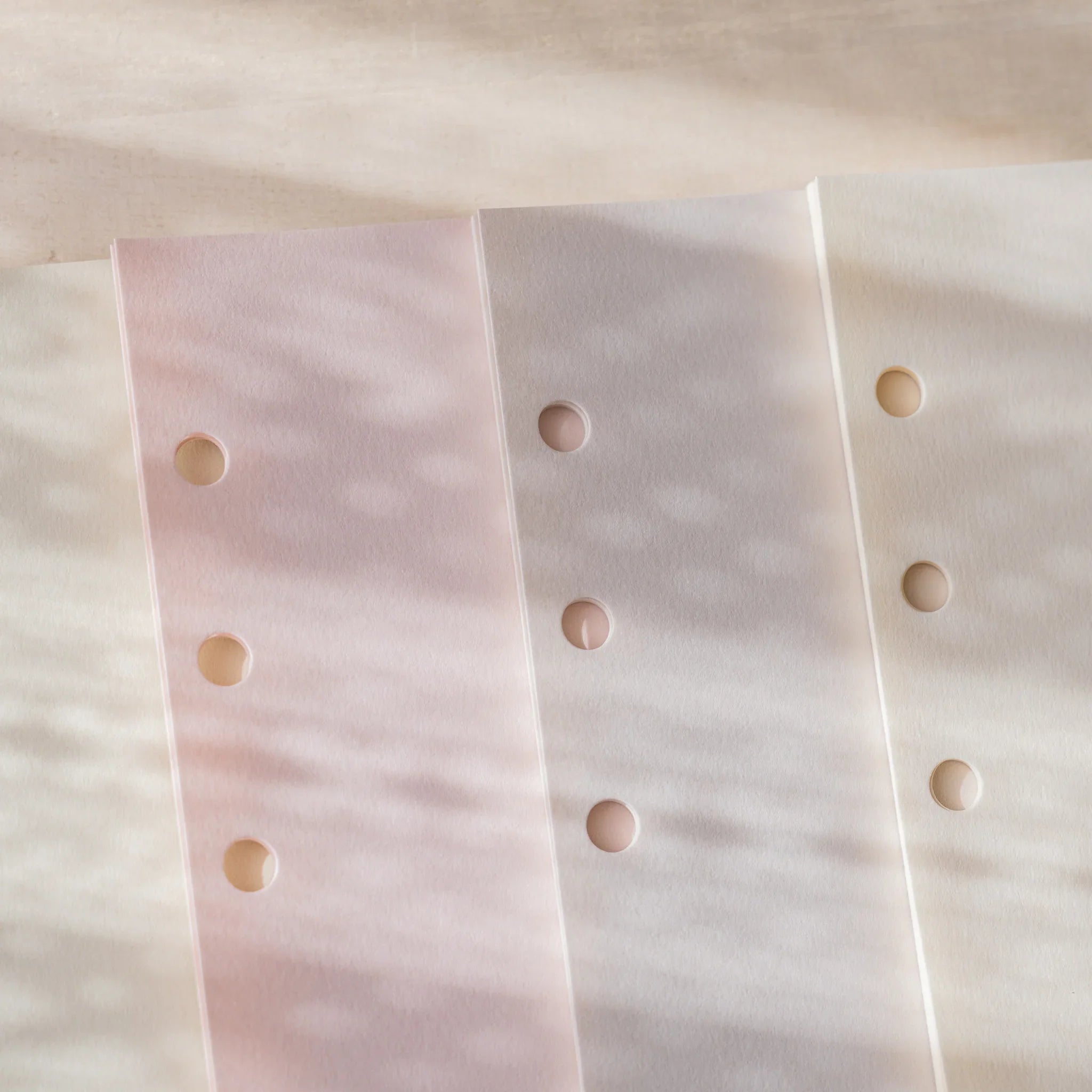 Three lighter Araveal planner refill colors close-up: primrose, ash gray, and natural showing 6-hole punch.