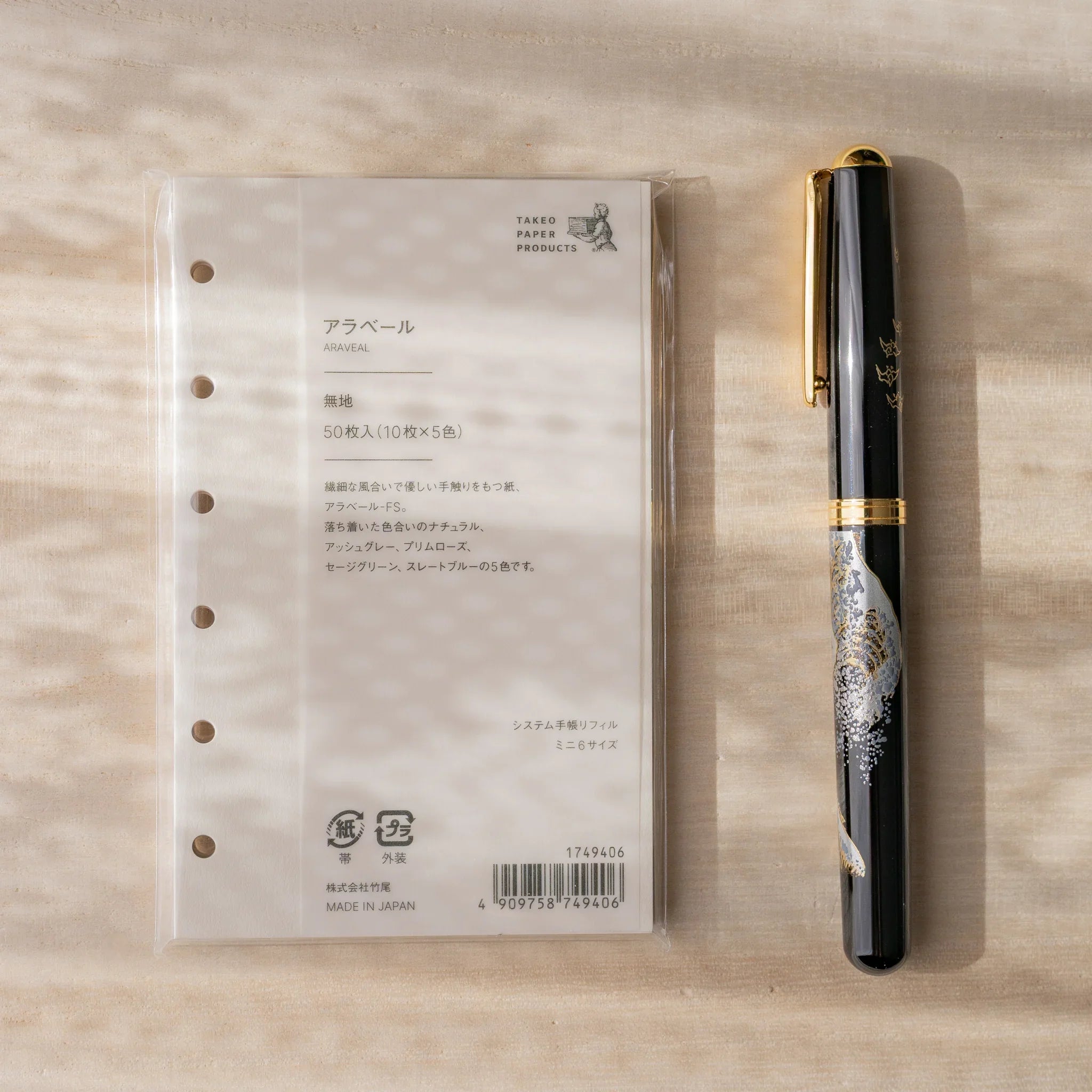 Takeo Paper Araveal Mini 6 planner refill packaging with a Japanese fountain pen alongside on a wood surface.