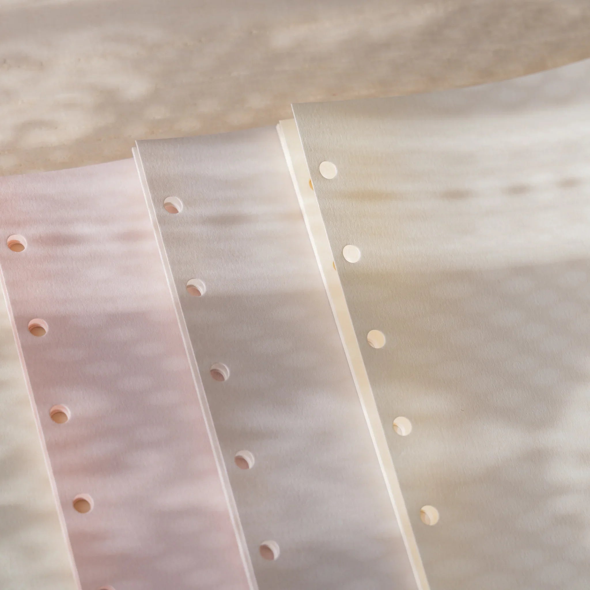Three Araveal Mini 6 planner refill colors close-up: primrose, ash gray, and natural showing translucency.