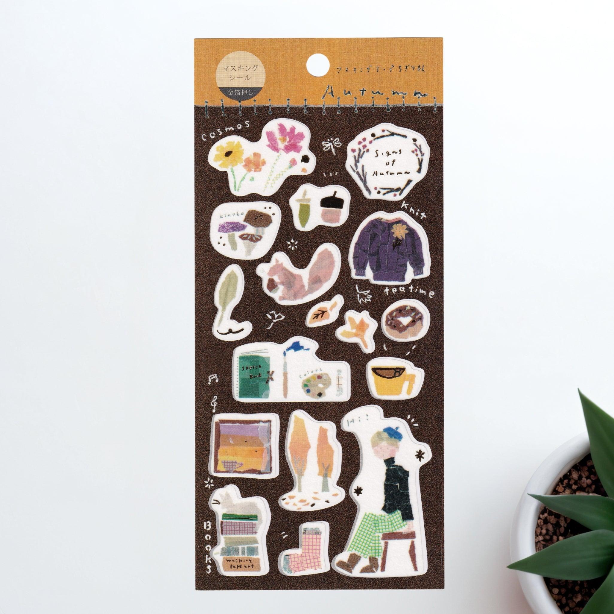 A Japanese stationery washi sticker sheet featuring autumn-themed designs, including cozy sweaters, falling leaves, books, tea time, and seasonal flowers, in a warm watercolor style.