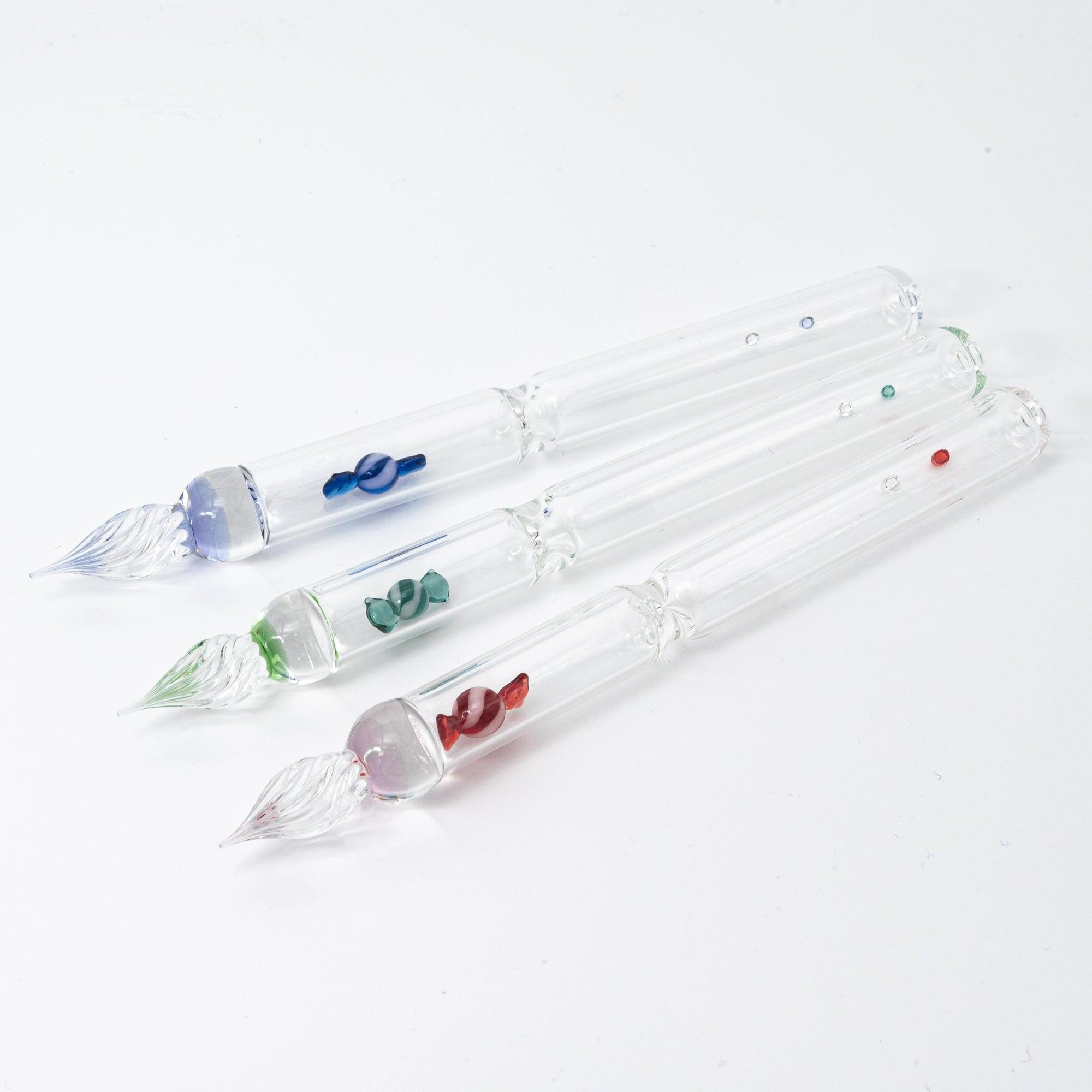 Three glass dip pens, each featuring a colorful candy motif in blue, green, and red, encased in the clear glass, bringing a fun twist to your writing tools.