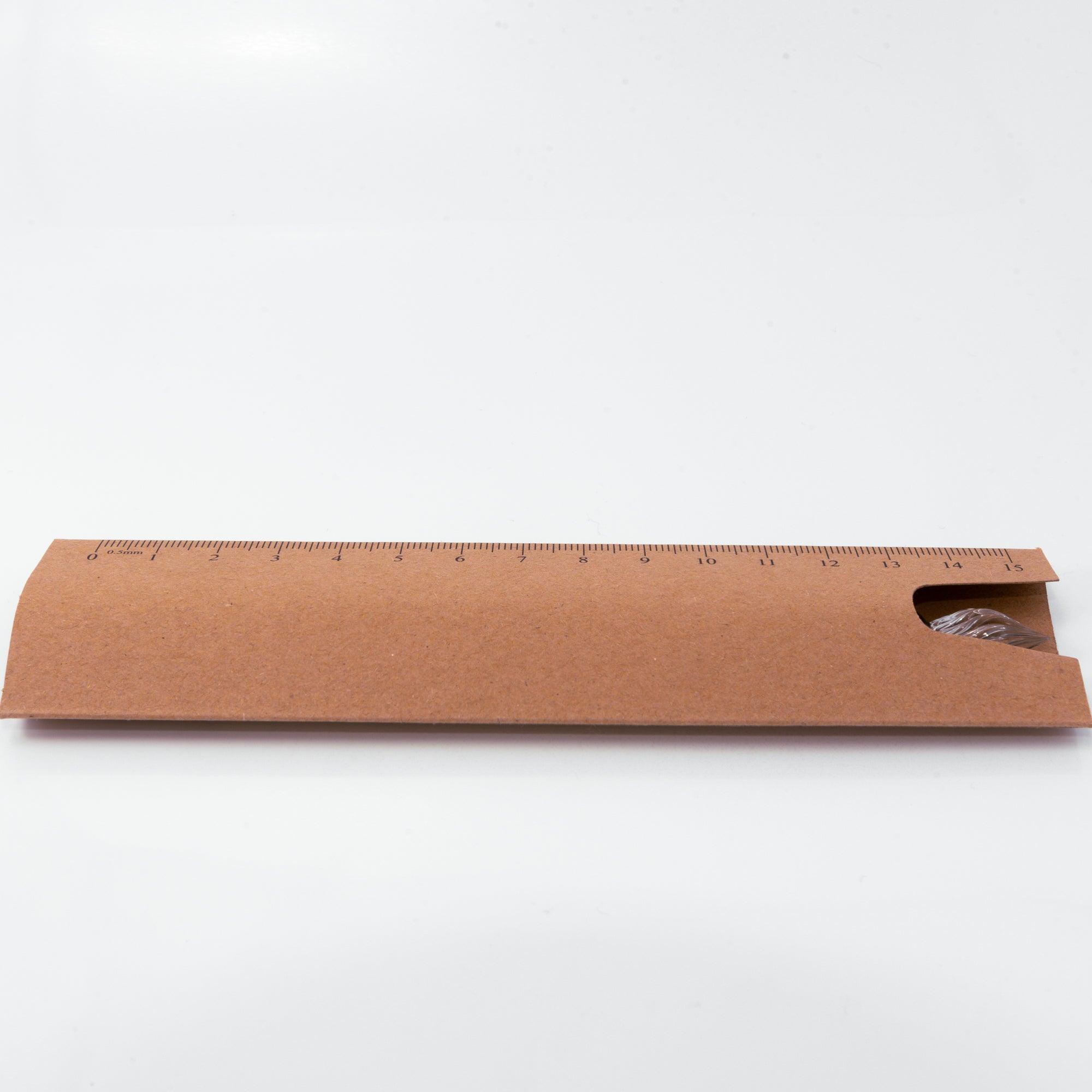 Brown kraft paper packaging featuring a printed ruler, with the tip of a glass dip pen peeking out.