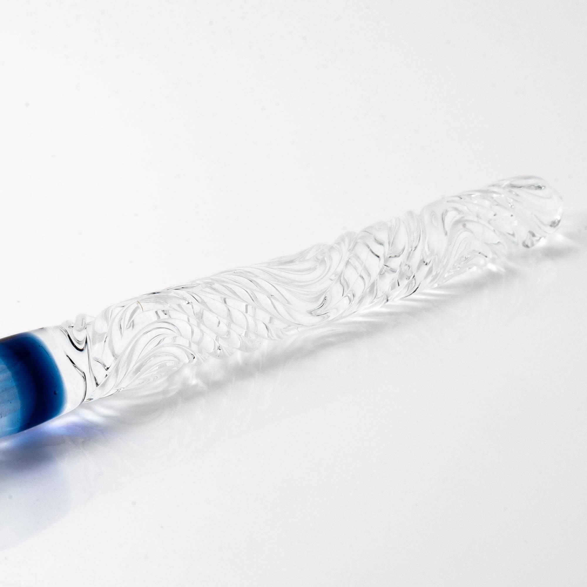 A delicate glass pen with an intricate blue rose motif, resting on a clear pen holder.