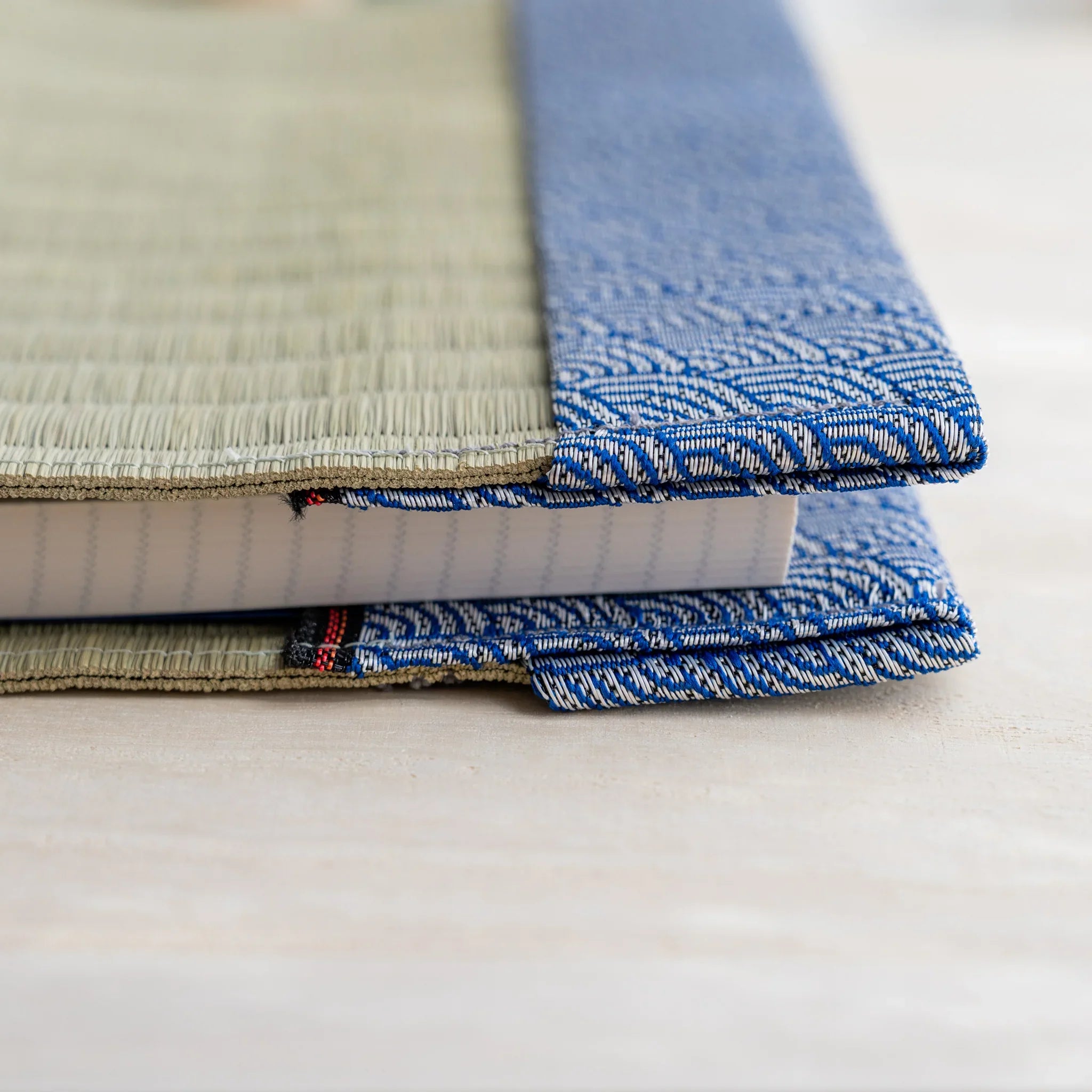 Side view of tatami book cover with notebook inserted, showing thickness and folded wave pattern fabric flap