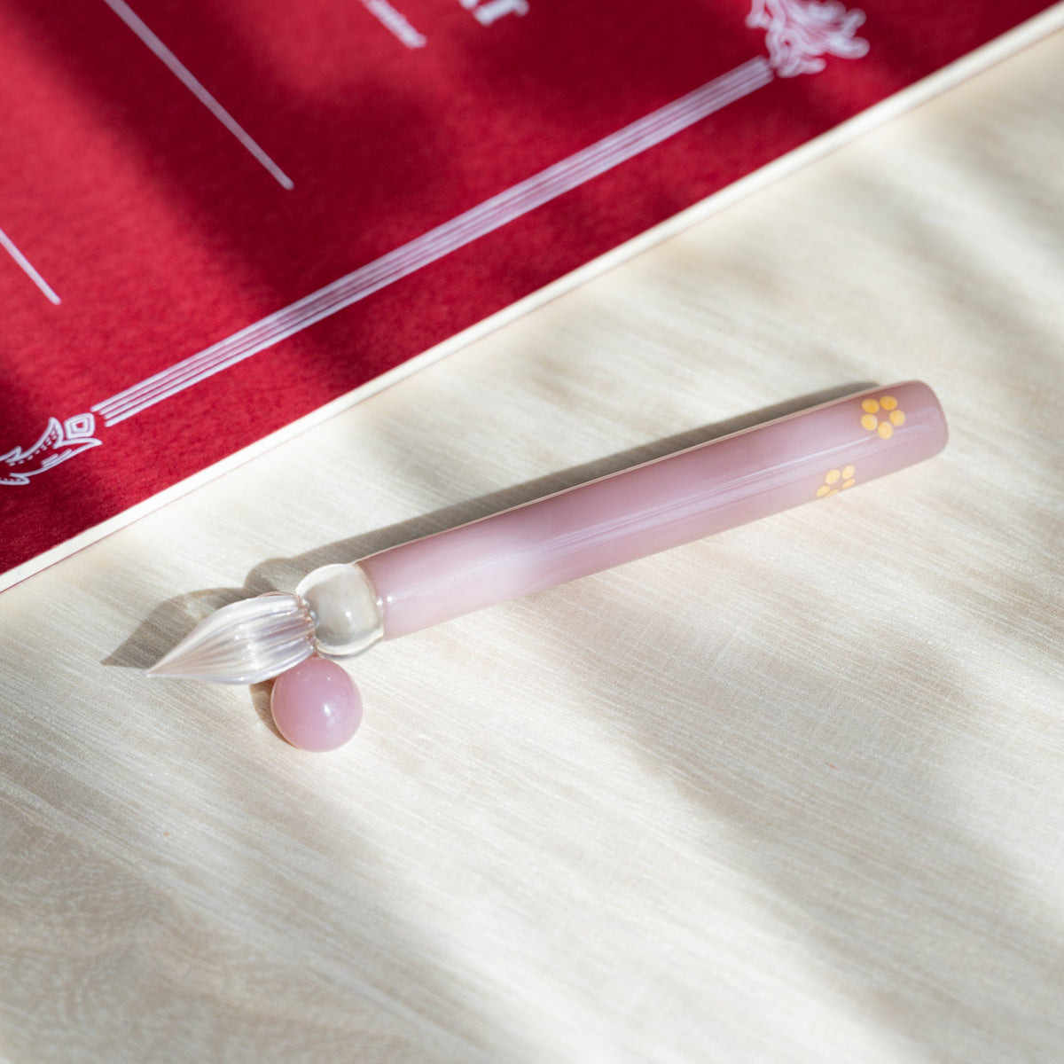 Blush Pink Flowers glass dip pen angled nib down on pale wood with a red printed card behind