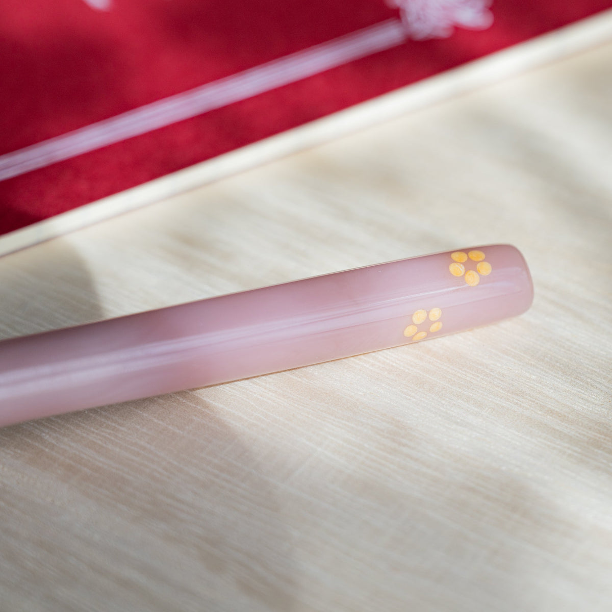 Detail of a yellow five-petal blossom set into the pale pink glass barrel