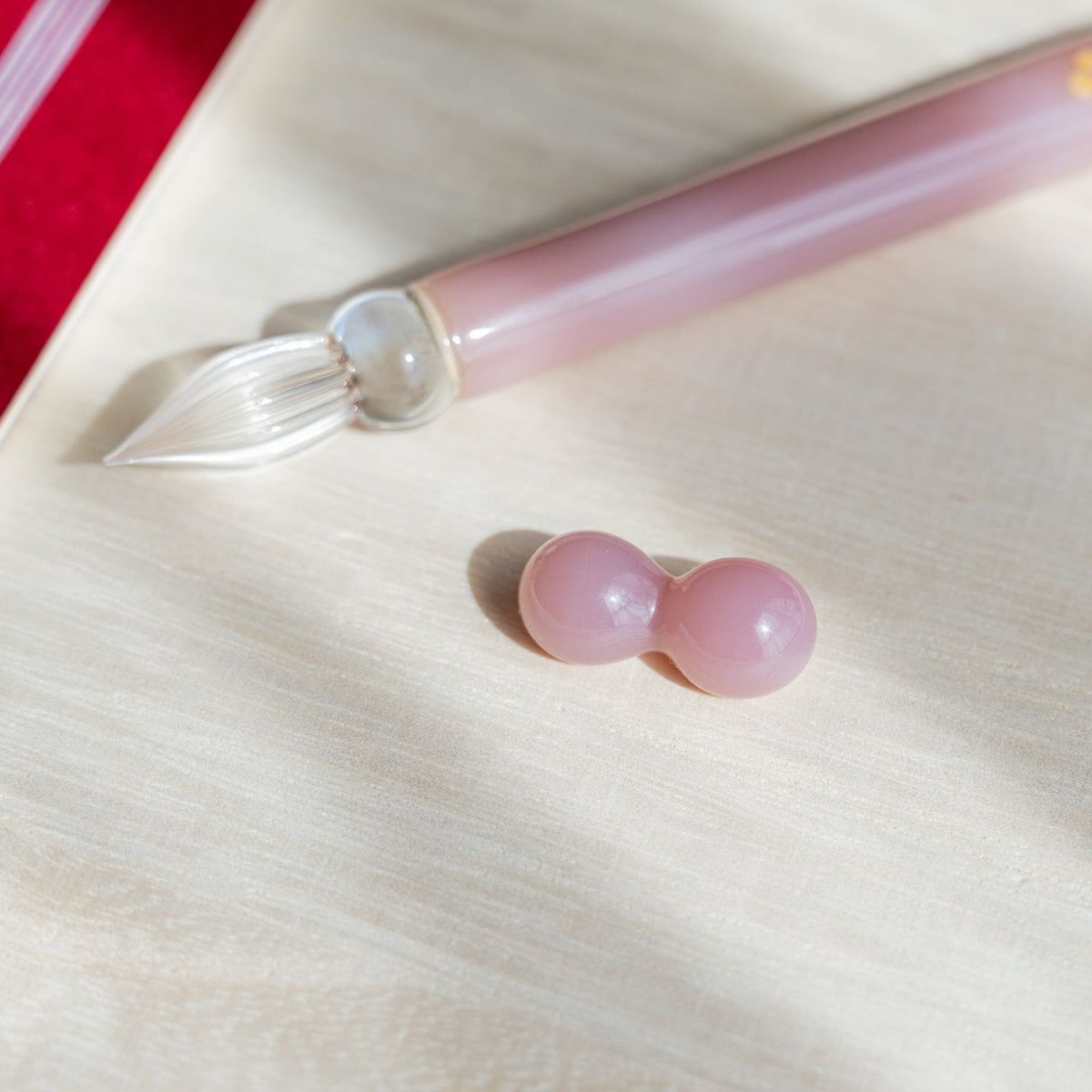 Clear nib and pale pink barrel of the Blush Pink Flowers pen with its two-sphere glass pen rest