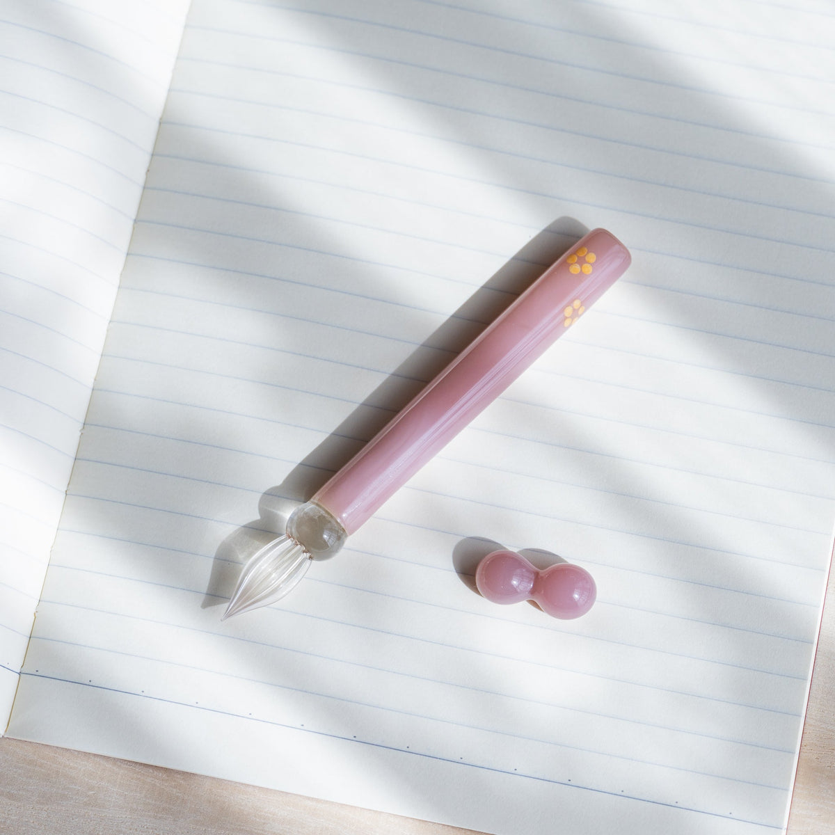 Blush Pink Flowers glass dip pen and pink glass pen rest lying on a sheet of lined paper