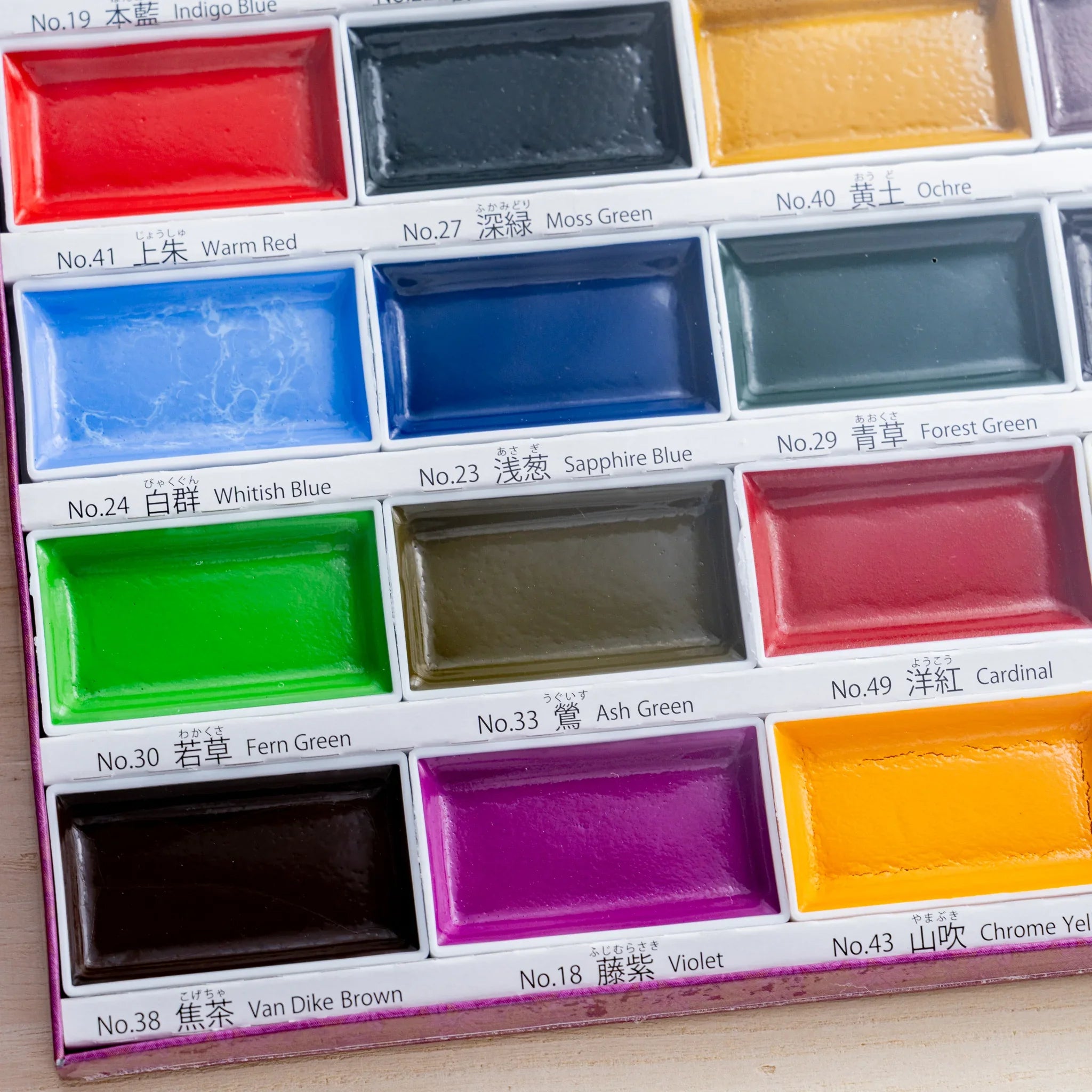 Close-up of lower portion of Boku-Undo Gansai 24-color watercolor box showing twelve pans with traditional color labels