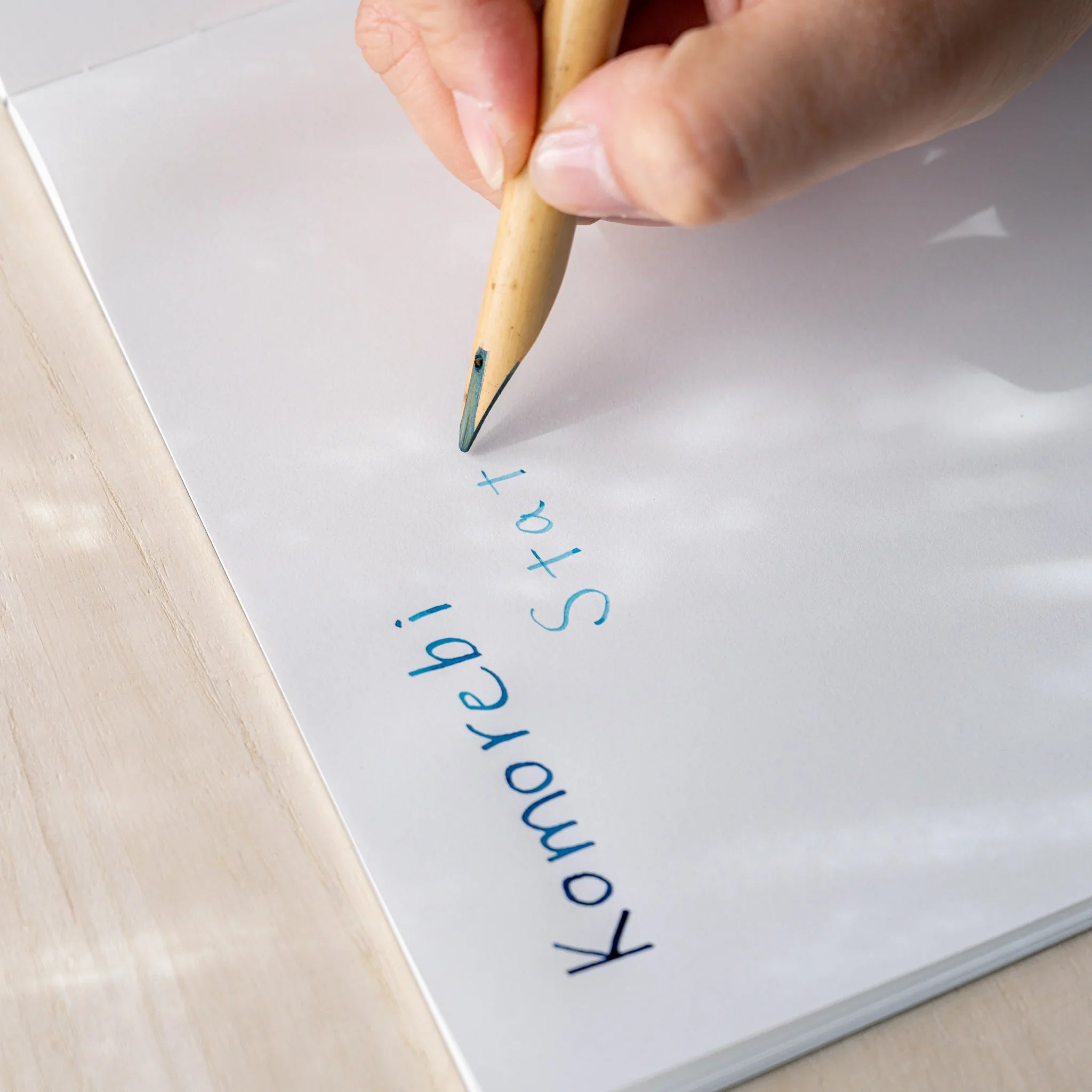 Hand writing "Komorebi Stationery" in blue ink on white paper using Boku-Undo bamboo dip pen