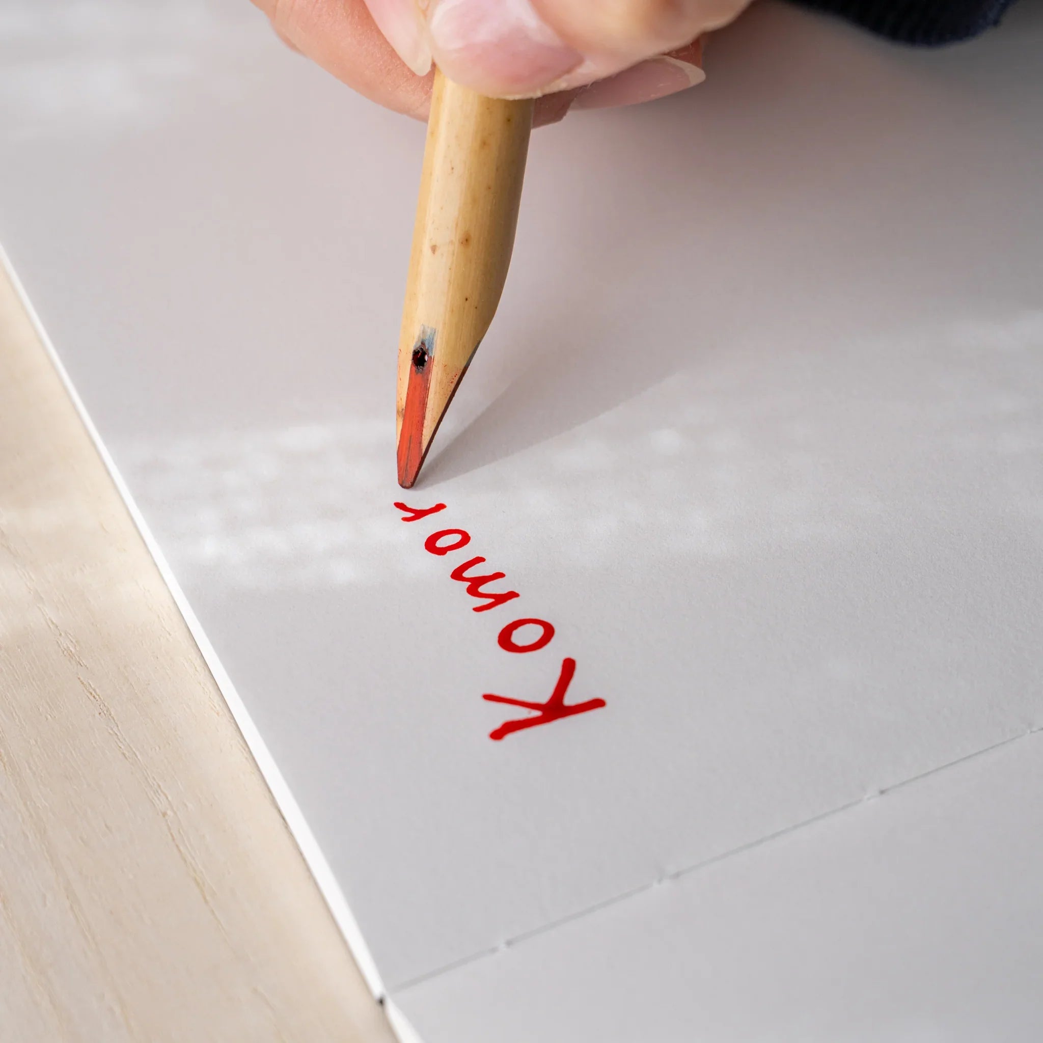 Hand writing Komorebi in red ink on white paper using Boku-Undo bamboo dip pen