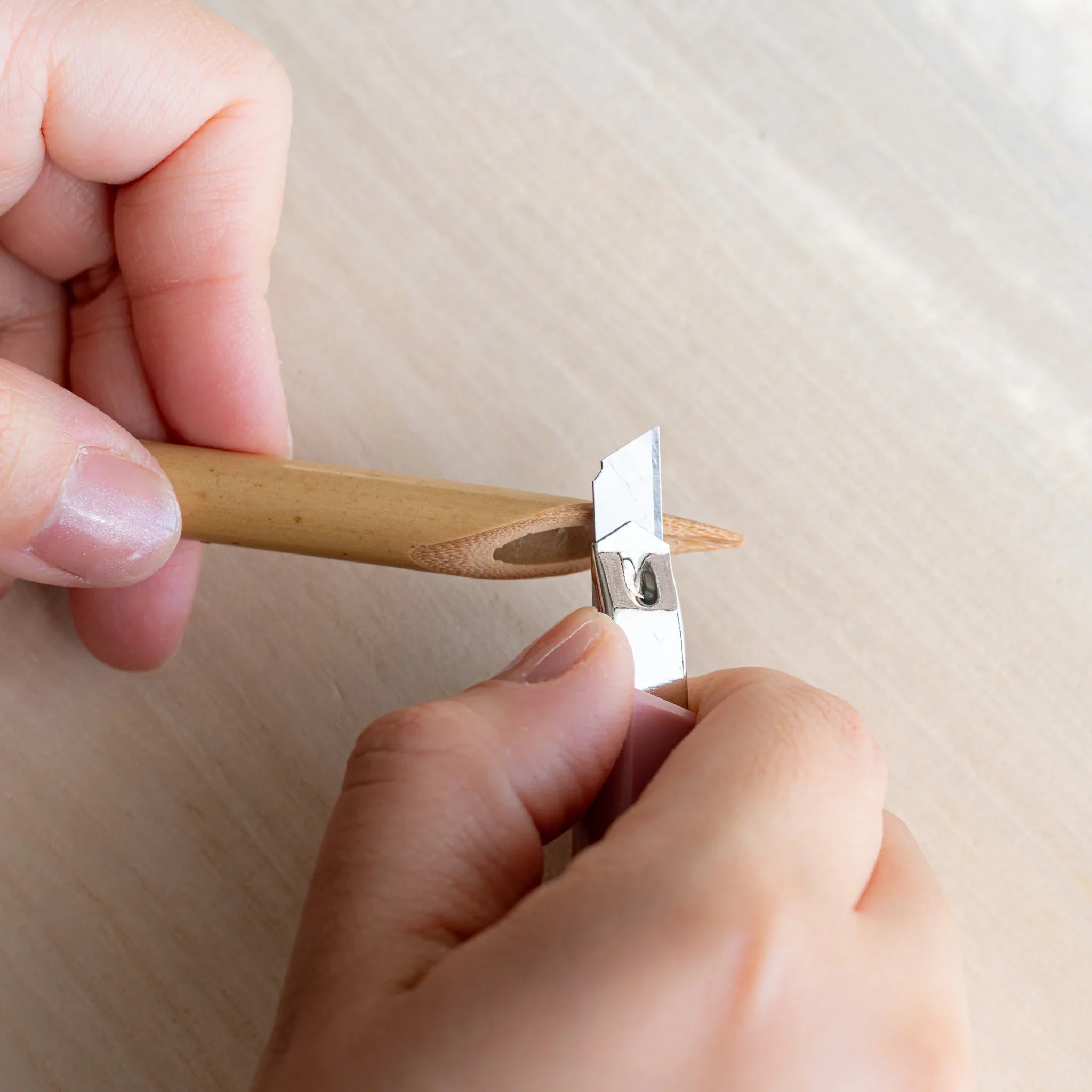 Hands trimming the Boku-Undo bamboo dip pen nib with a metal blade to customize the tip width
