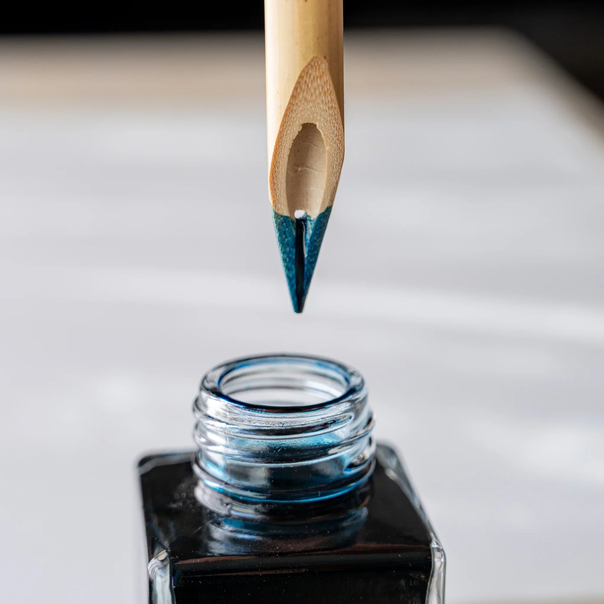 Boku-Undo bamboo dip pen nib lifted from ink bottle with blue-black ink on tip, open ink bottle below