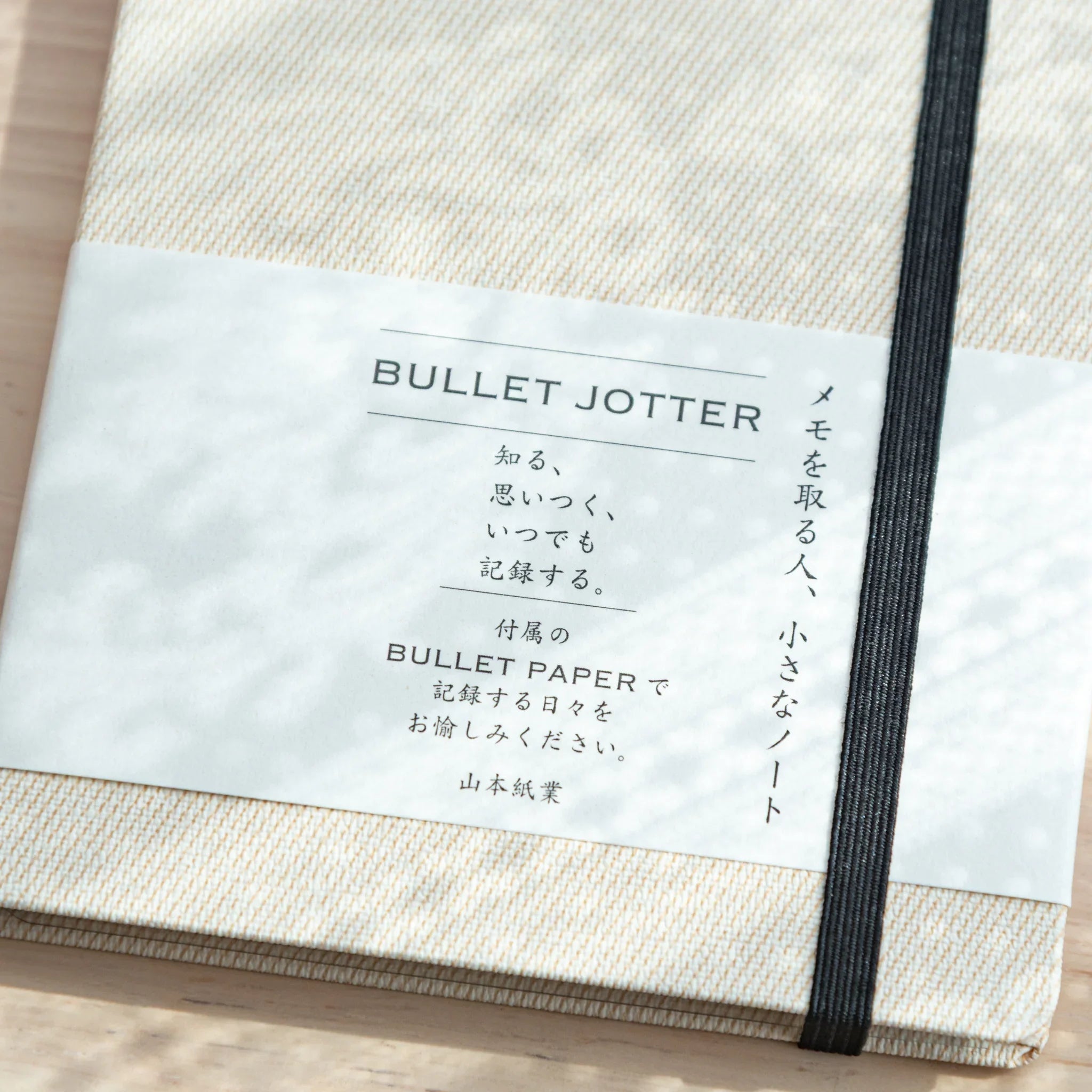 Front cover of Bullet Jotter Japanese Writing Pad – Gabardine Ivory White, with elastic band and label.