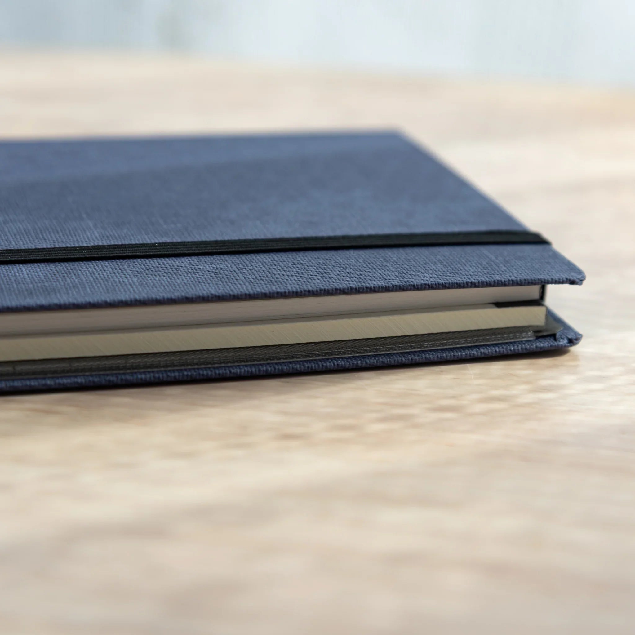 Side view of Japanese Writing Pad case in blue fabric with elastic band closure.