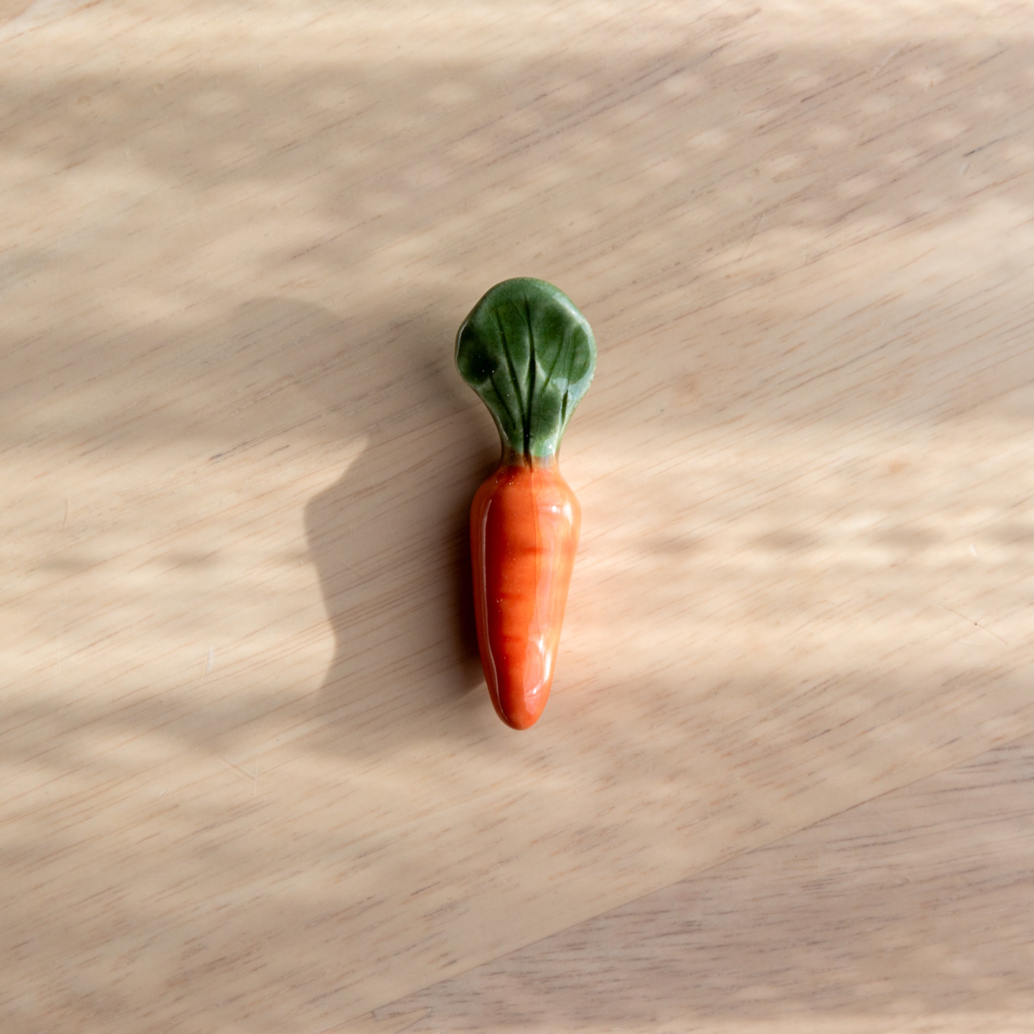 A handmade ceramic pen rest shaped as a carrot, showcasing Japanese stationery craftsmanship and playful natural motifs.