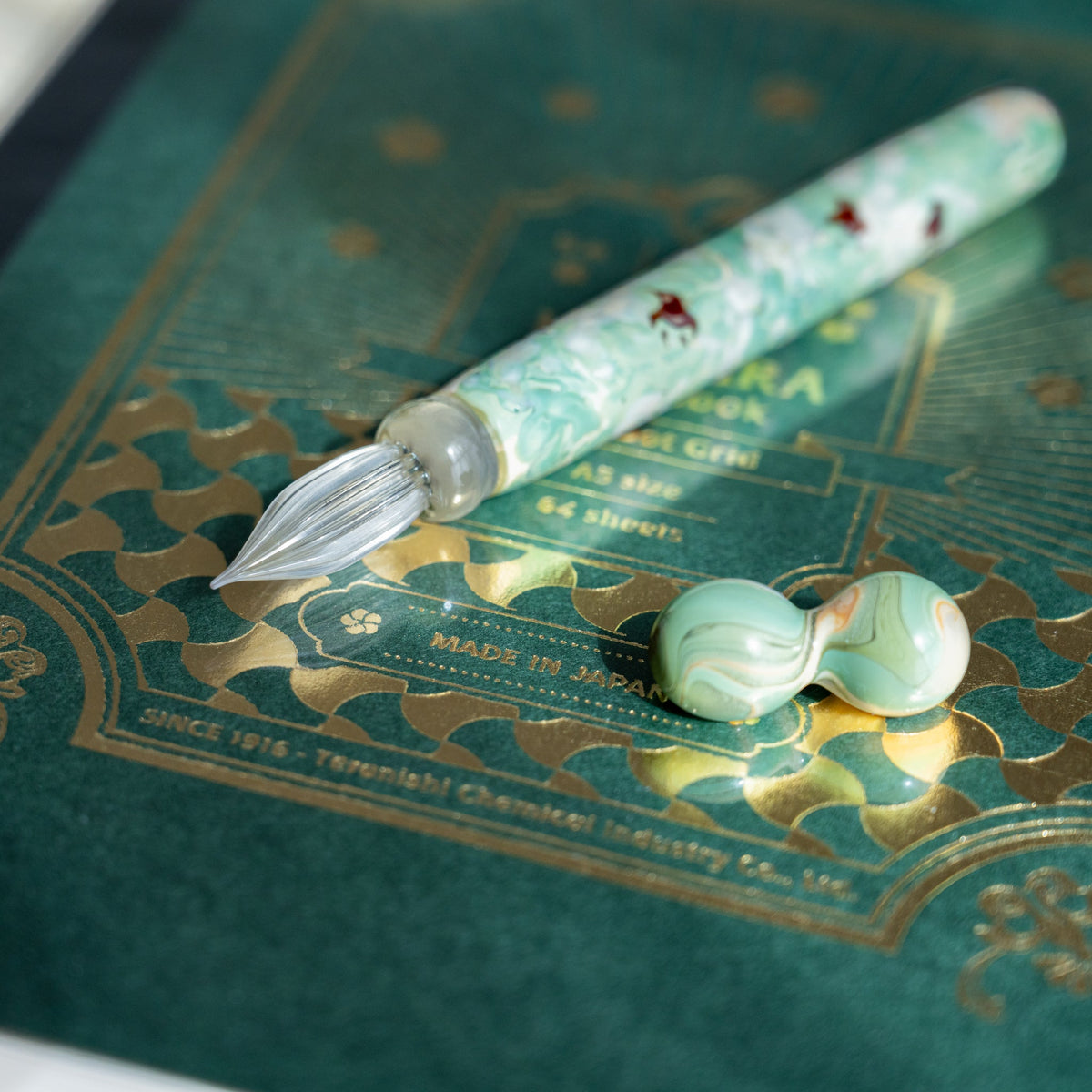 Chidori Mint Marble glass dip pen on a green notebook cover printed Made in Japan in gold foil
