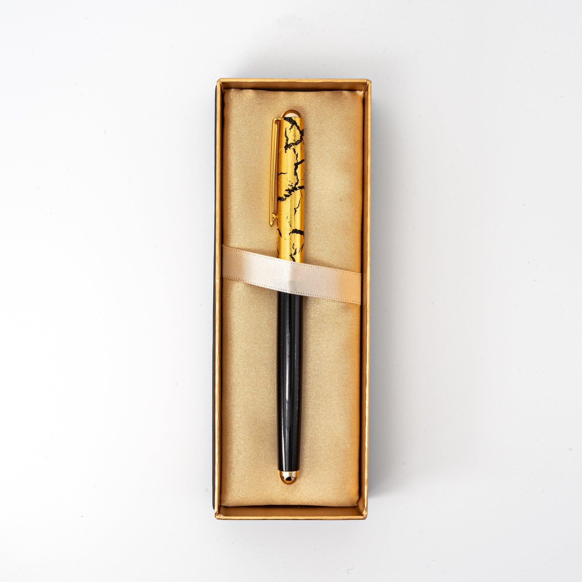 A black ballpoint pen with a gold crack pattern cap, elegantly displayed in a satin-lined box, ideal for gifting.