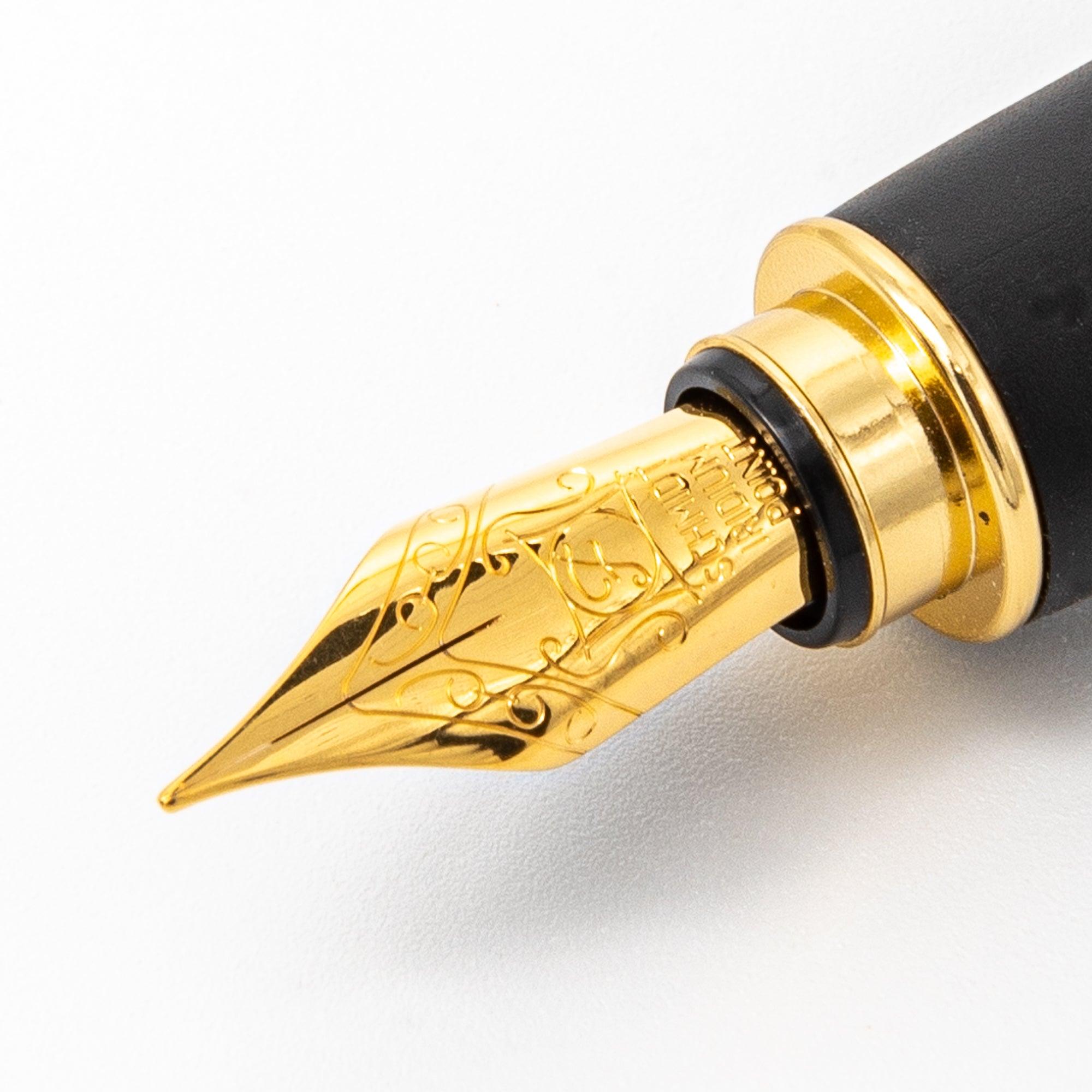 Close-up of a gold fountain pen nib featuring intricate engravings, smooth finish, and a black grip section.