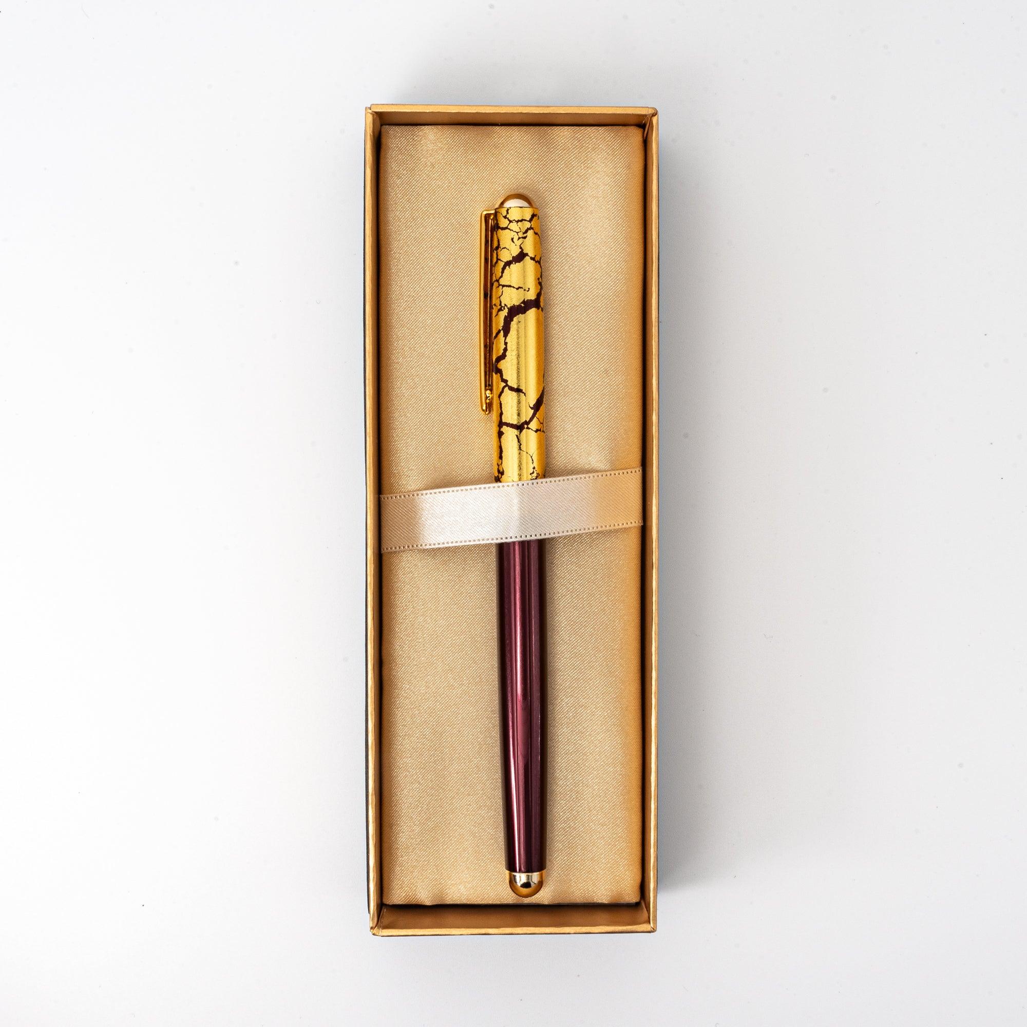 A wine-red ballpoint pen with a gold crack pattern cap, elegantly displayed in a satin-lined box, highlighting its luxurious design.