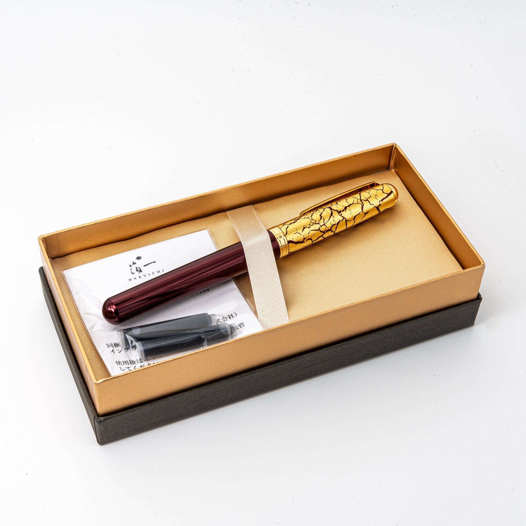 Wine-red Japanese fountain pen with a crackled gold-leaf cap, elegantly displayed in a gold-lined gift box with ink cartridges included.