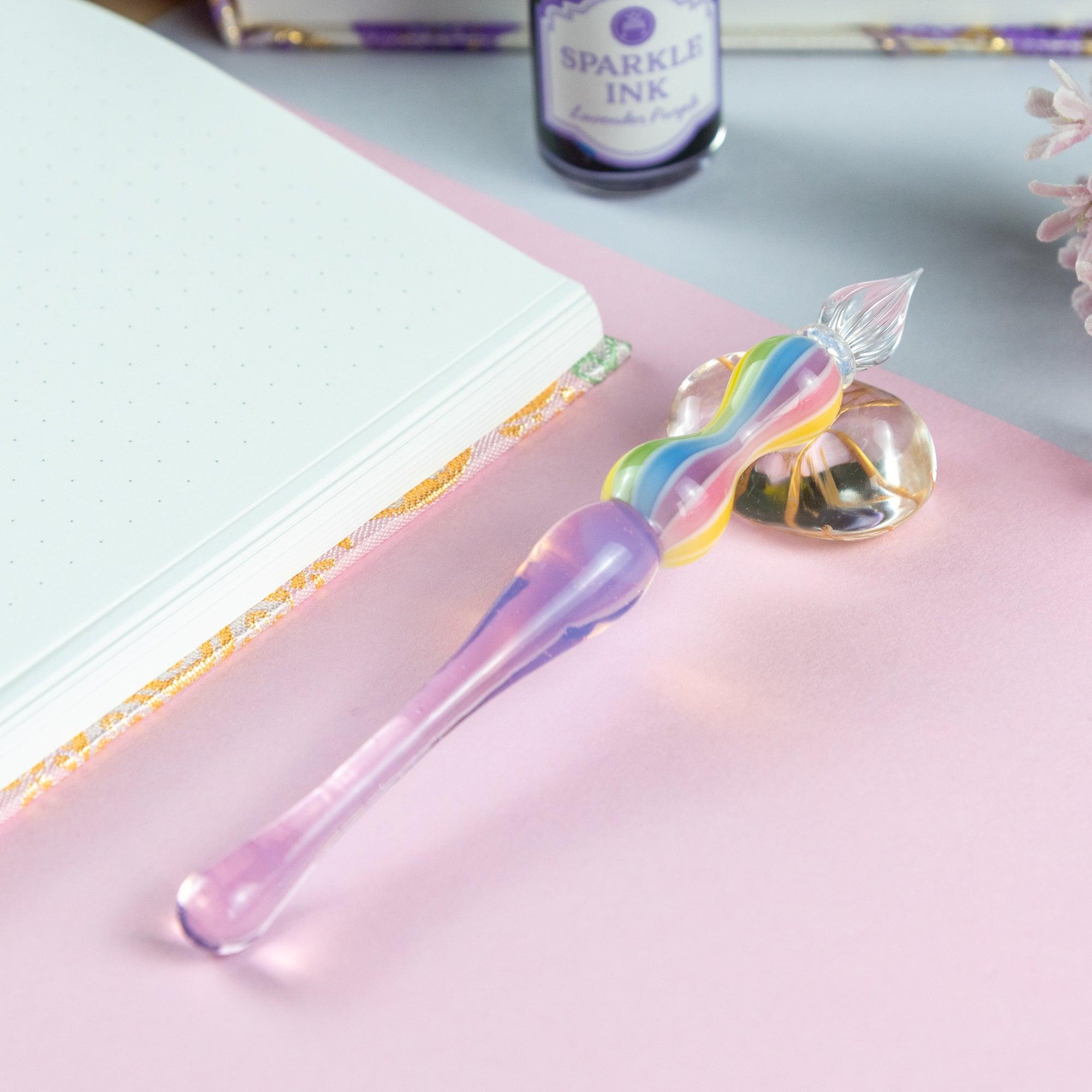 Glass pen with rainbow-colored handle placed on a white desk. Great for Japanese stationery lovers.