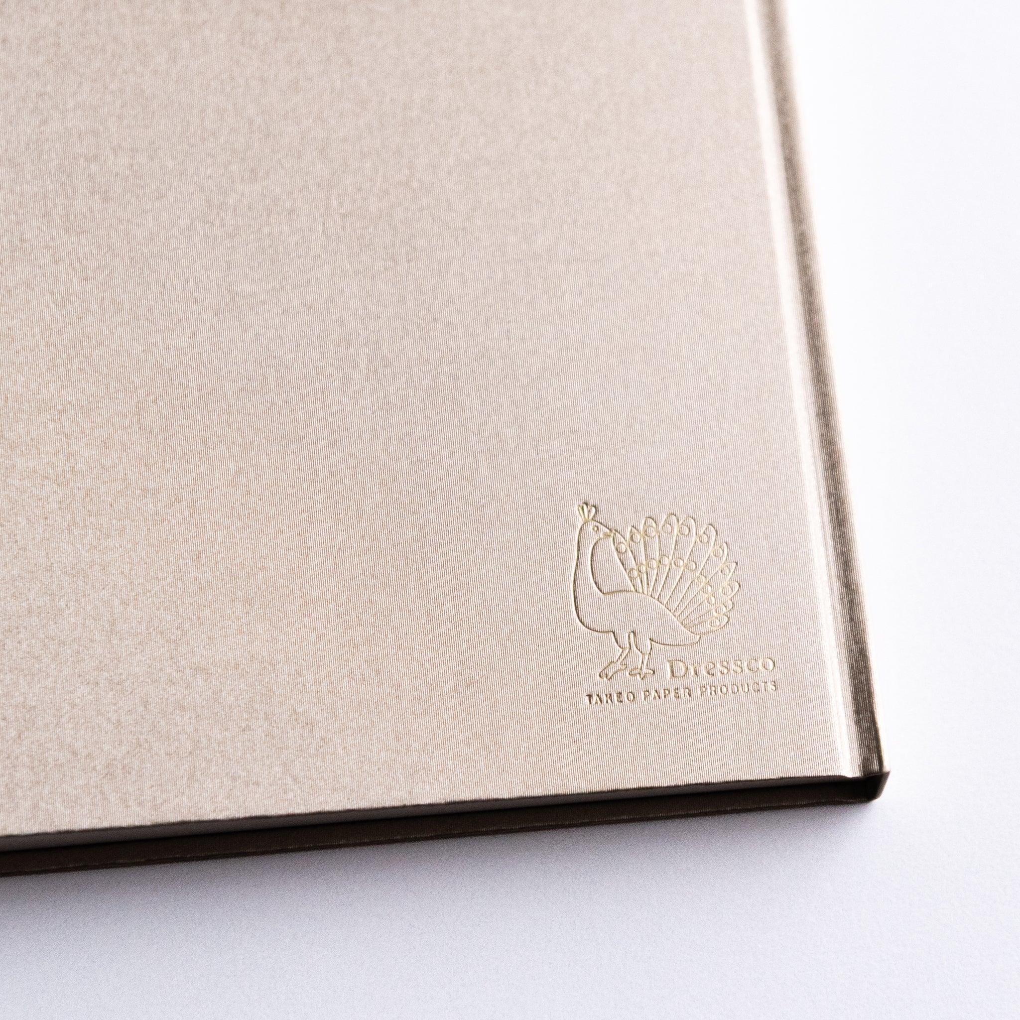 Close-up of embossed logo on Dressco Bank Ledger Paper Japanese Notebook in Champagne Gold.