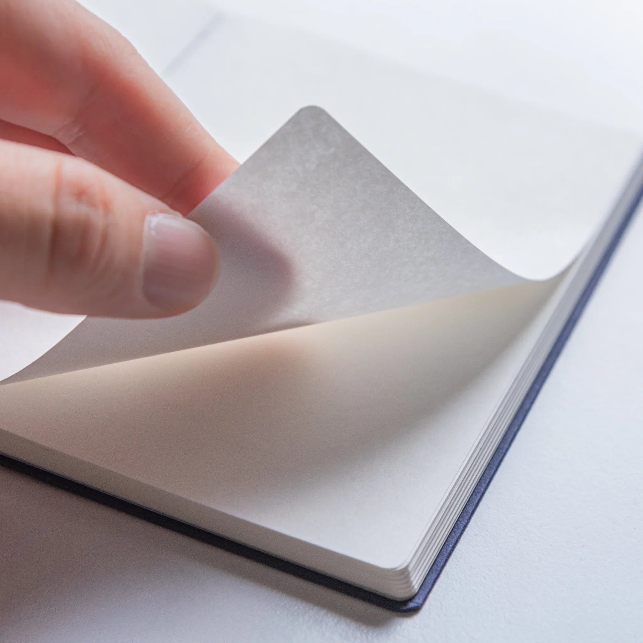 Close-up of page being turned in Dressco Bank Ledger Paper Japanese Notebook in Navy Blue.