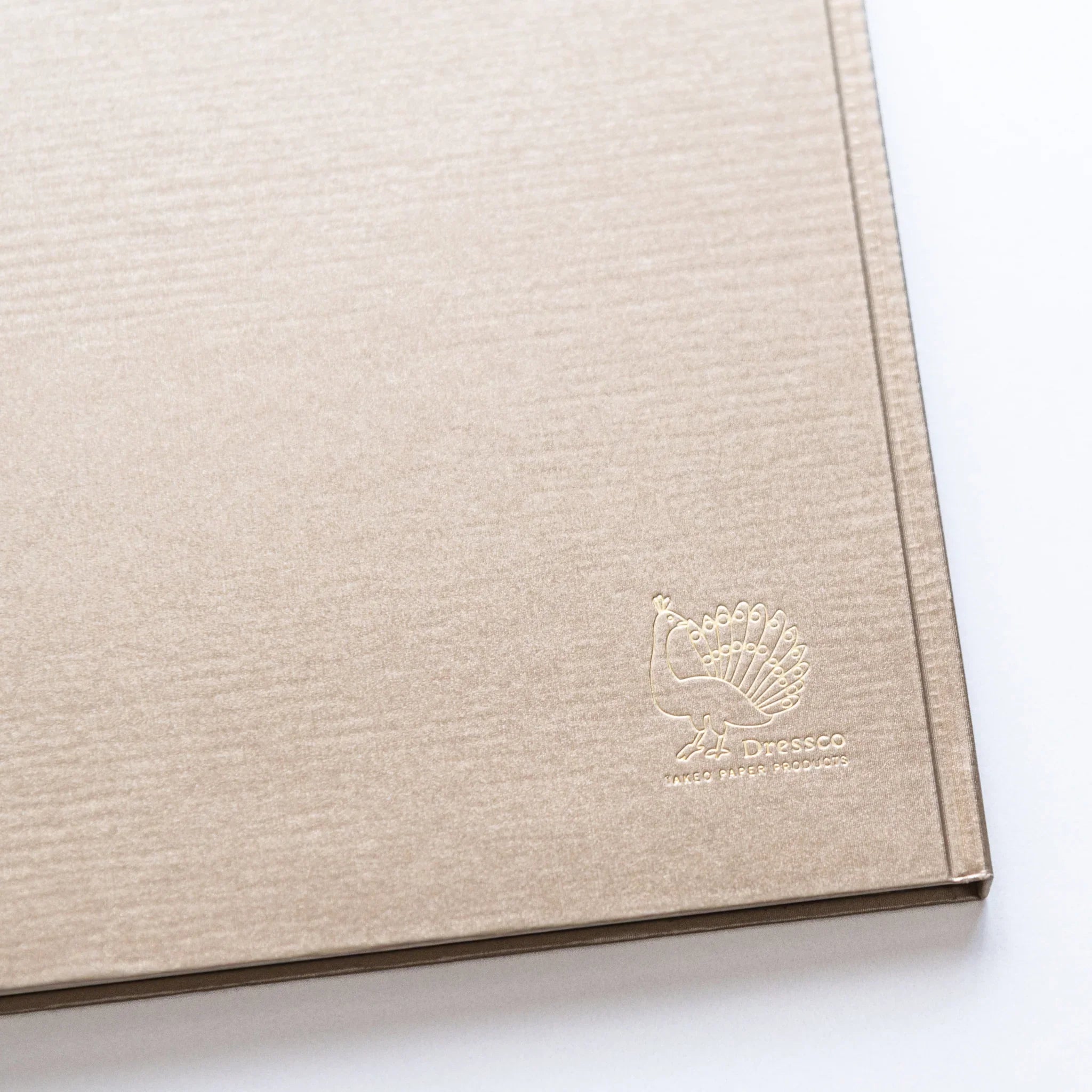Gold Dressco peacock logo embossed on Champagne Gold cover of Japanese Notebook.