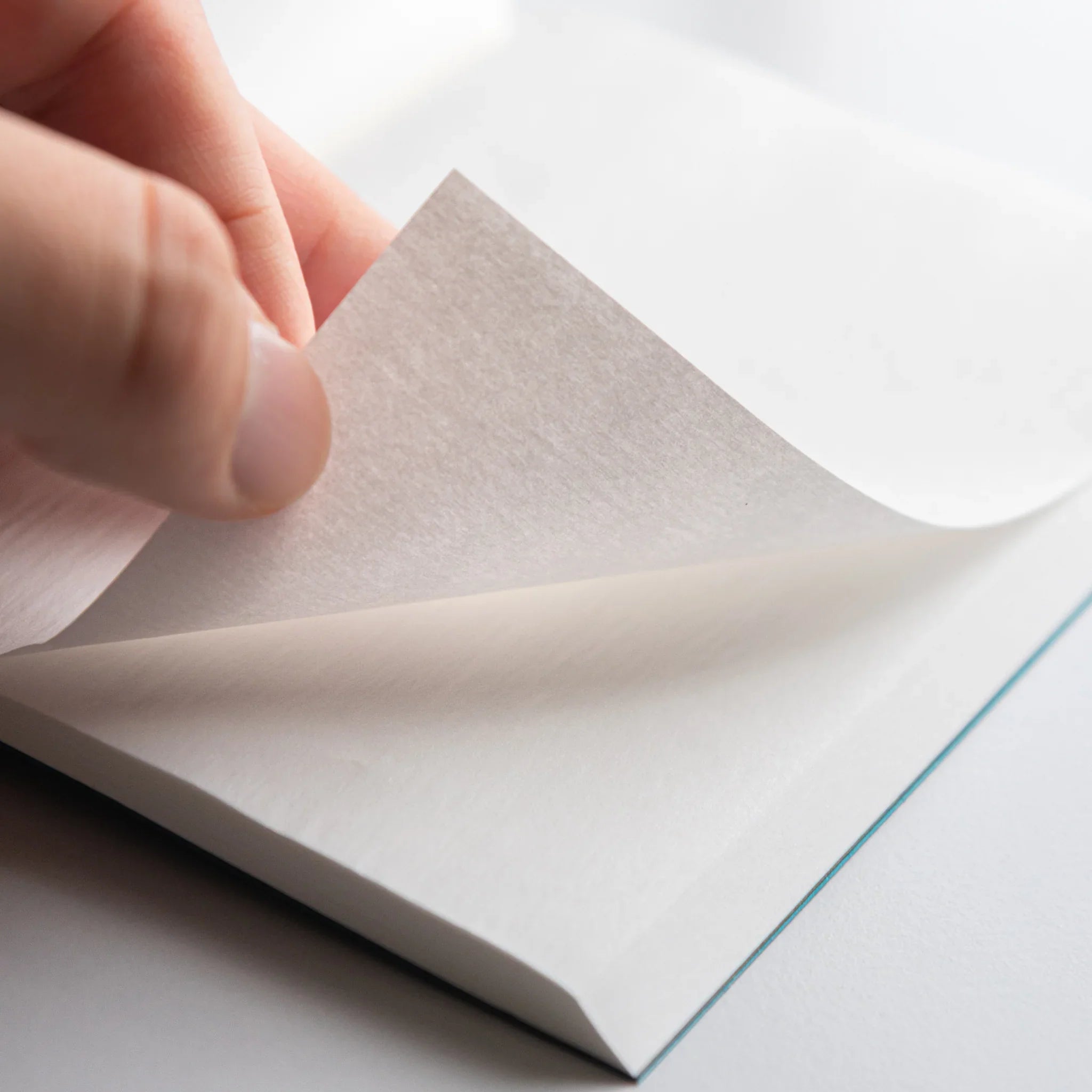 Hand flipping delicate pale blue onion-skin page of Dressco Blue Onion Skin Japanese Notebook showing translucence.