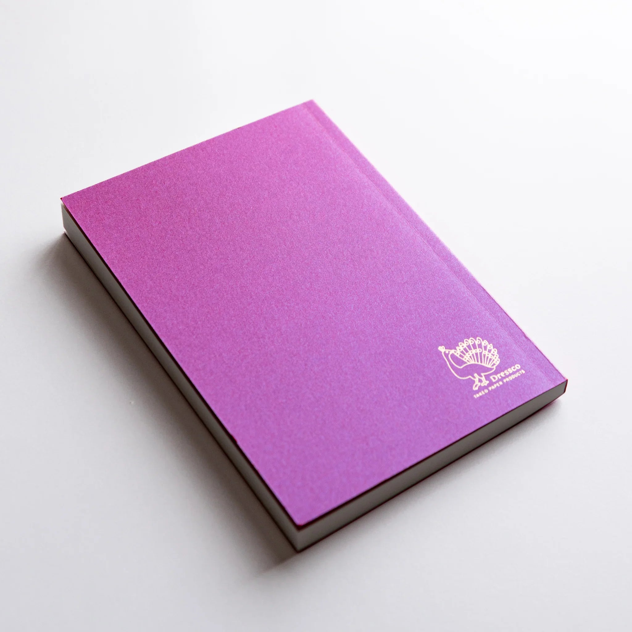 Dressco Pink Onion Skin Japanese Notebook A6 angled view with gold peacock logo embossed on the back cover.