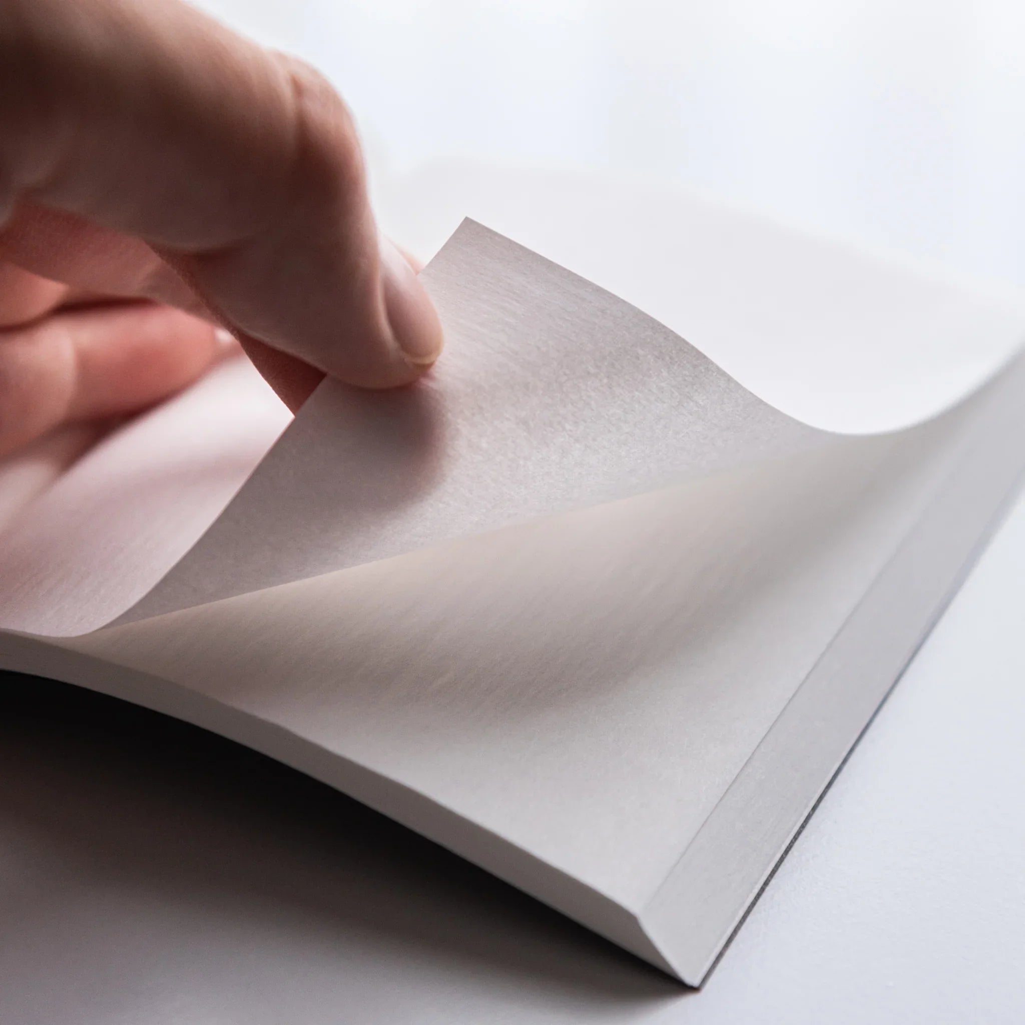 Hand flipping thin onion-skin page of Dressco Black Onion Skin Japanese Notebook showing translucence.