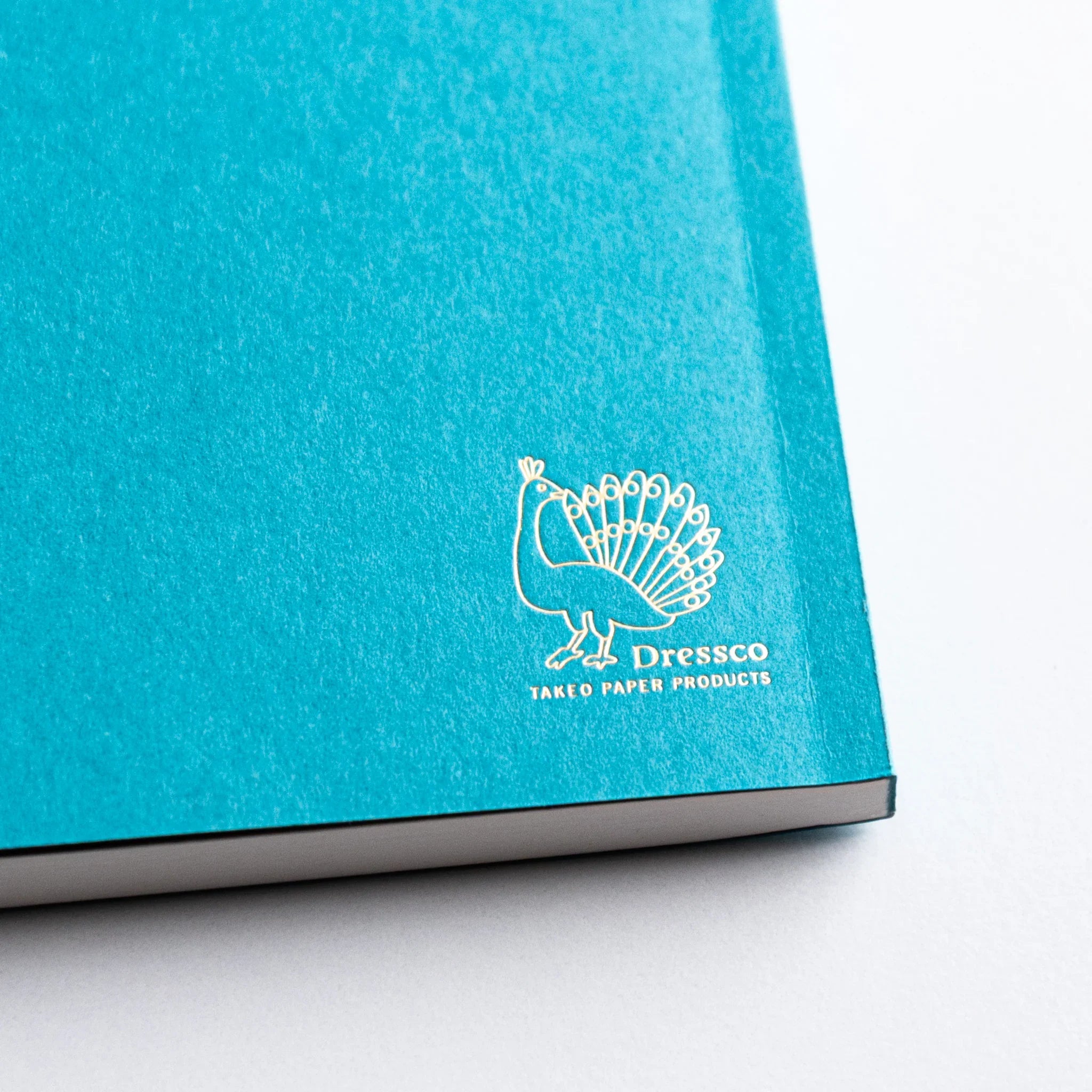 Back cover of Dressco Teal Blue Onion Skin Japanese Notebook A6 with gold peacock Dressco logo.