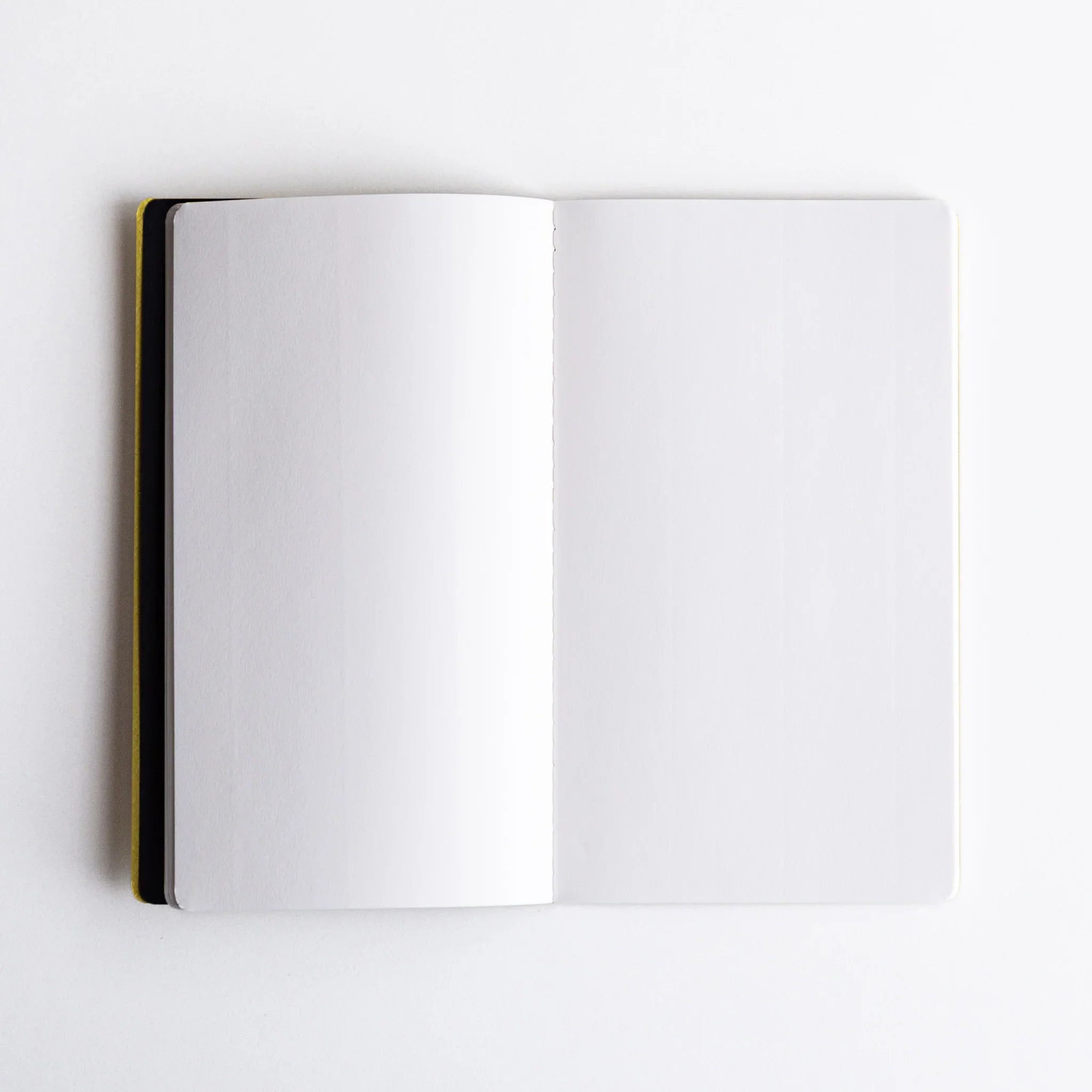 Open Japanese notebook of Spica Laid Bond Paper, showing blank white pages and a stitched spine with minimalist design.
