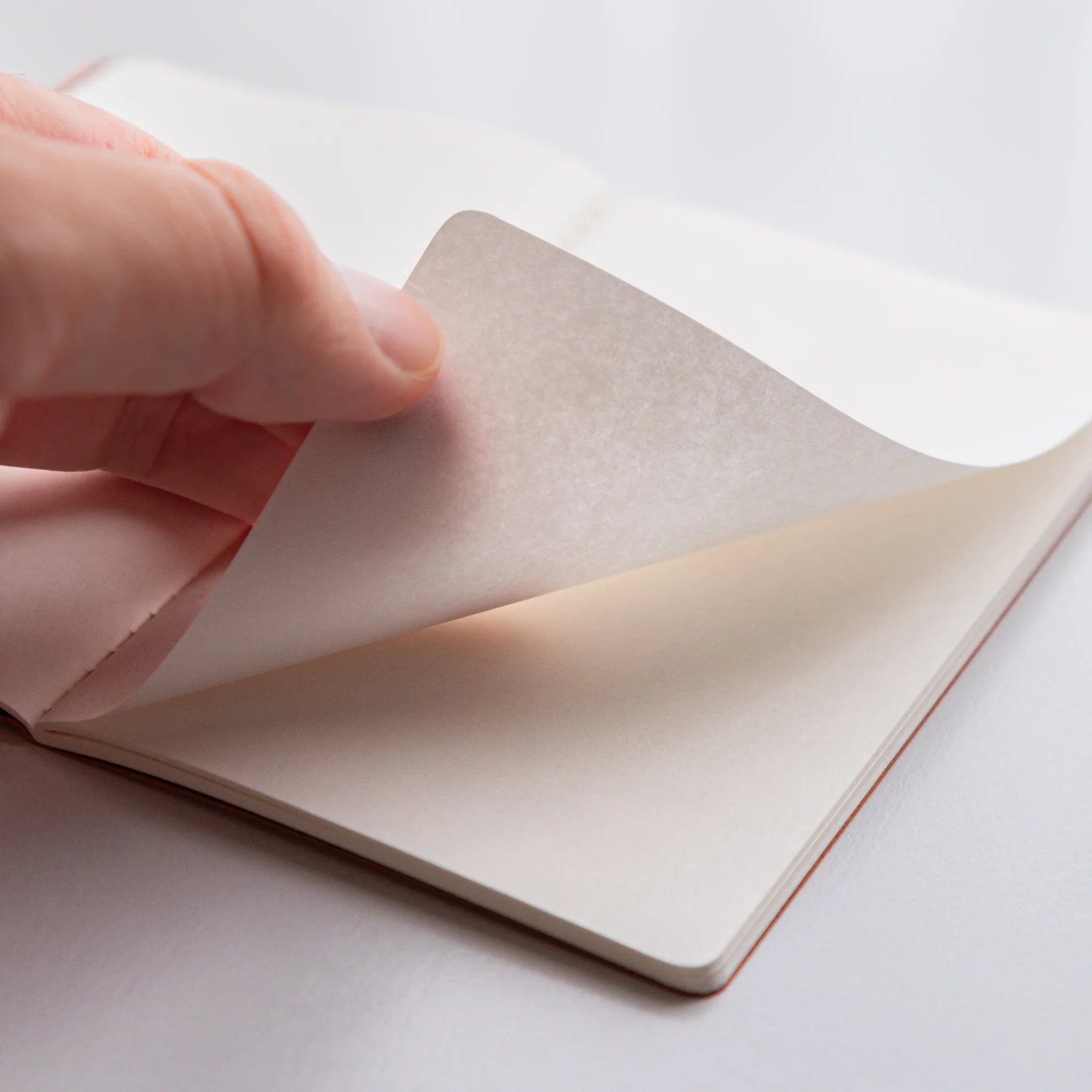 Hand turning a delicate page of Bank Ledger Paper Japanese notebook, highlighting tactile paper quality and craftsmanship.