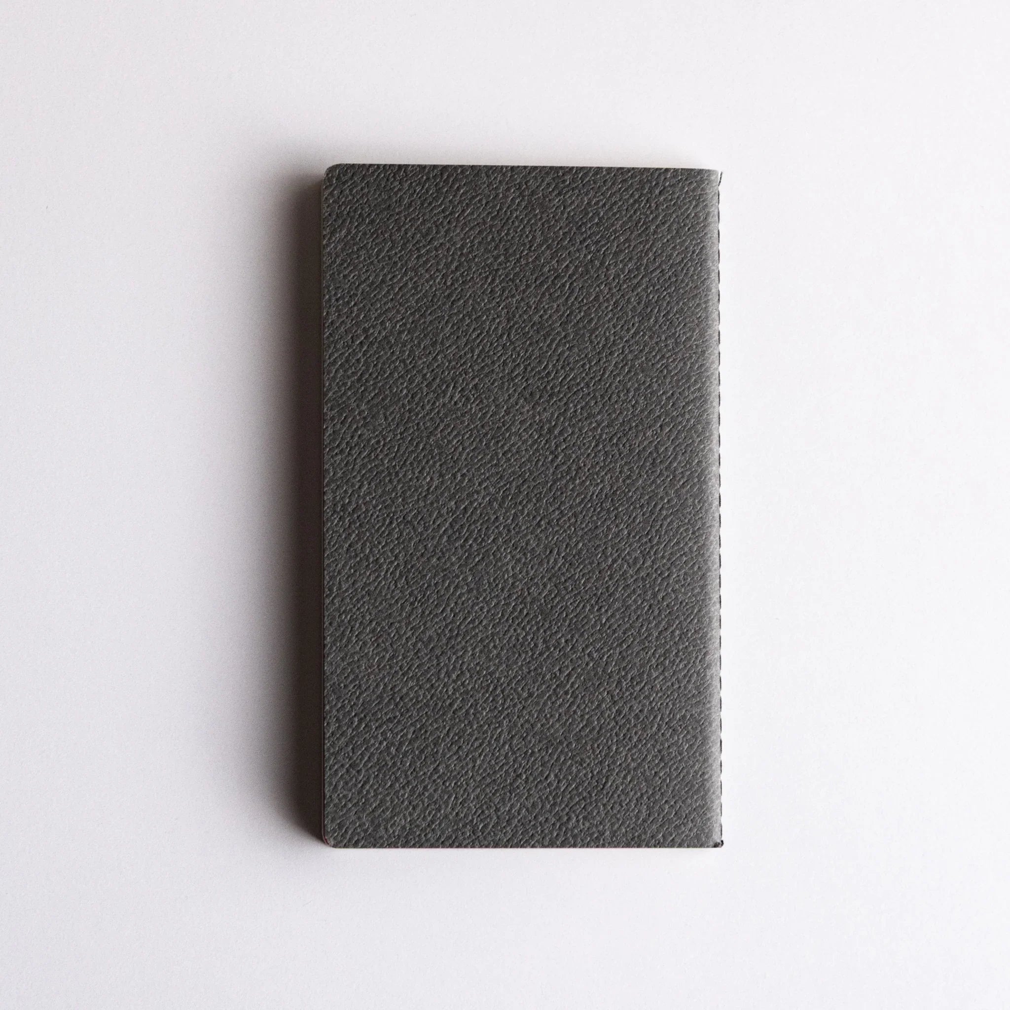 Japanese notebook made from Bank Ledger Paper featuring a textured dark gray cover and stitched binding, displayed on a white background.