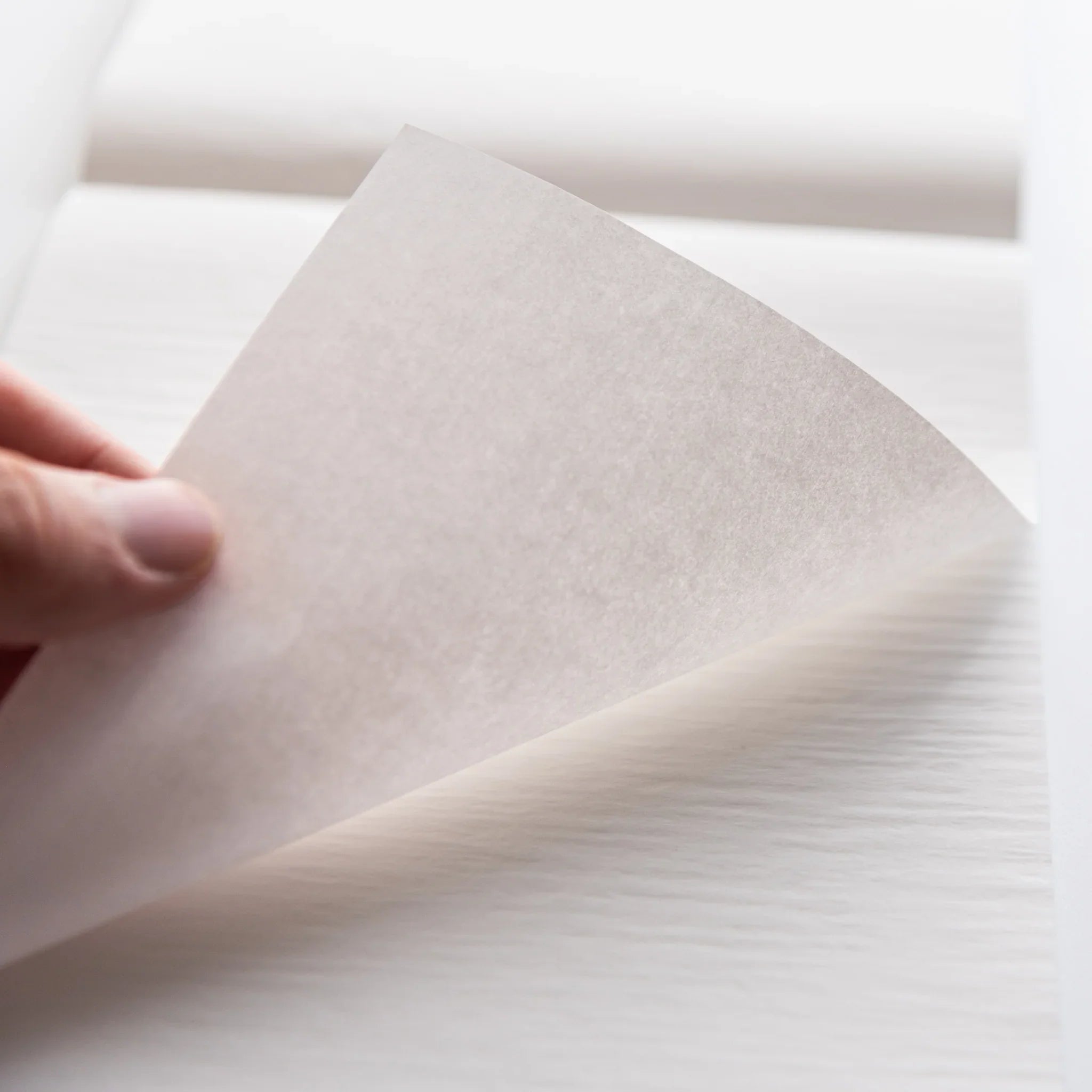 Close-up of thin translucent sheet from Dressco White Onion Skin Japanese Paper Writing Pad being lifted by hand.